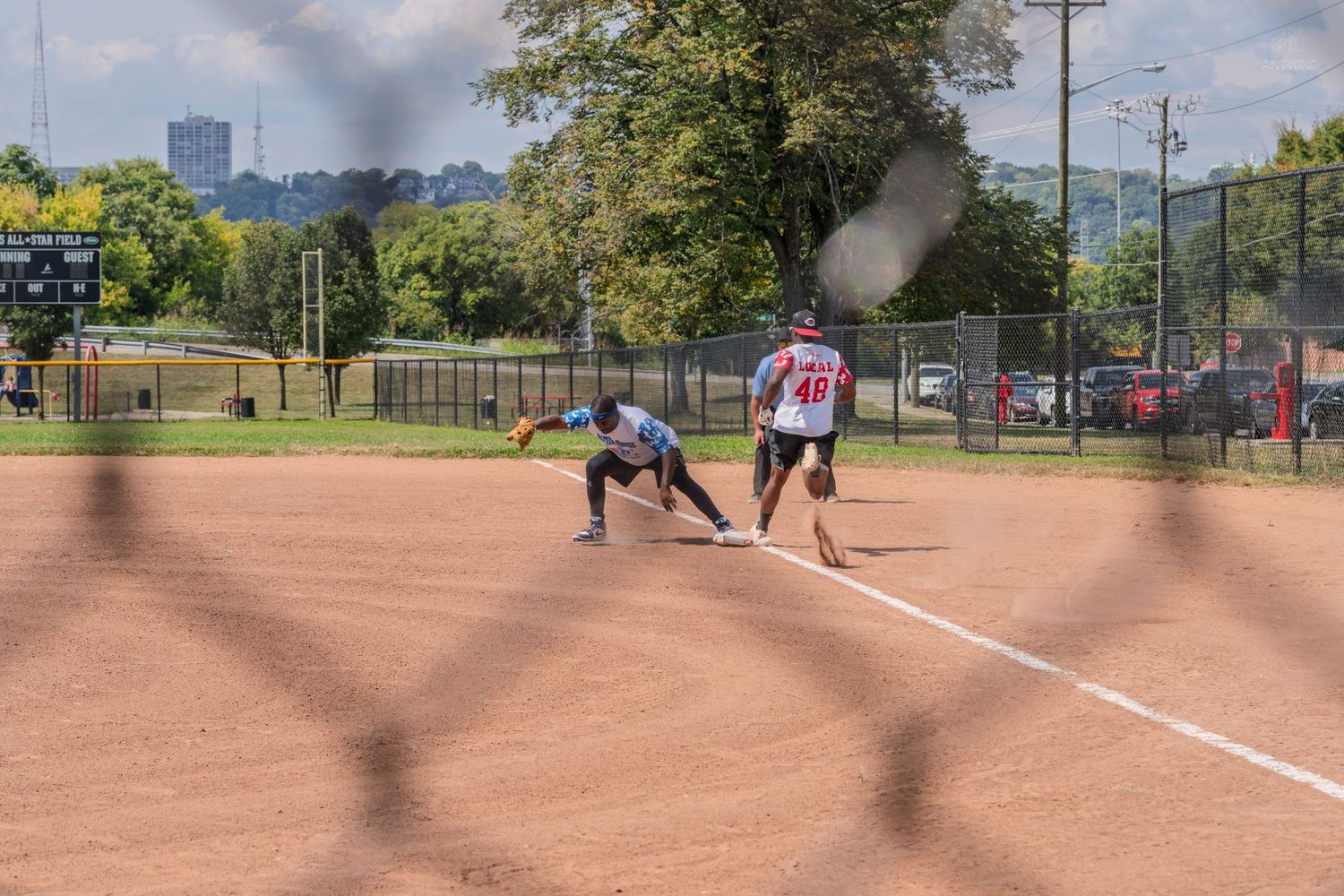 Two softball players on a dirt field during a recreational league game on a sunny day.