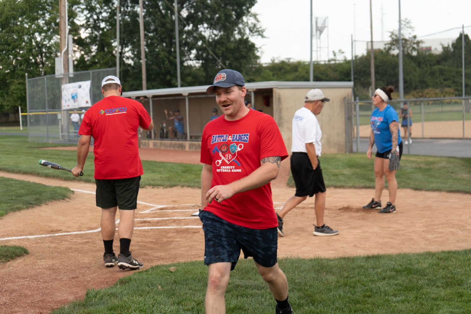 People playing recreational softball on a baseball diamond during an outdoor summer league game.