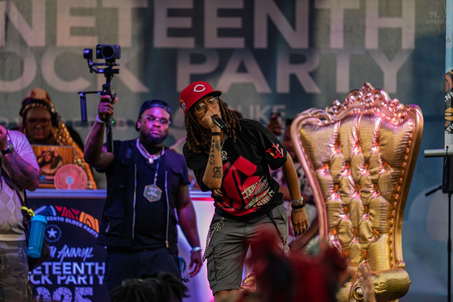 Performer raps into microphone at Juneteenth Block Party with videographer capturing the live show.