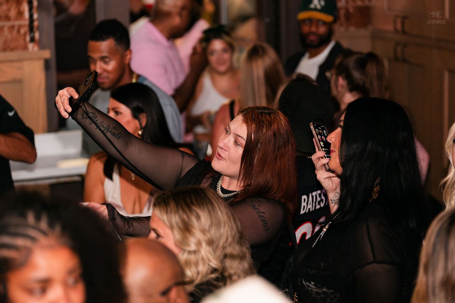 Woman taking a selfie with friends at a crowded nightlife bar or club event.