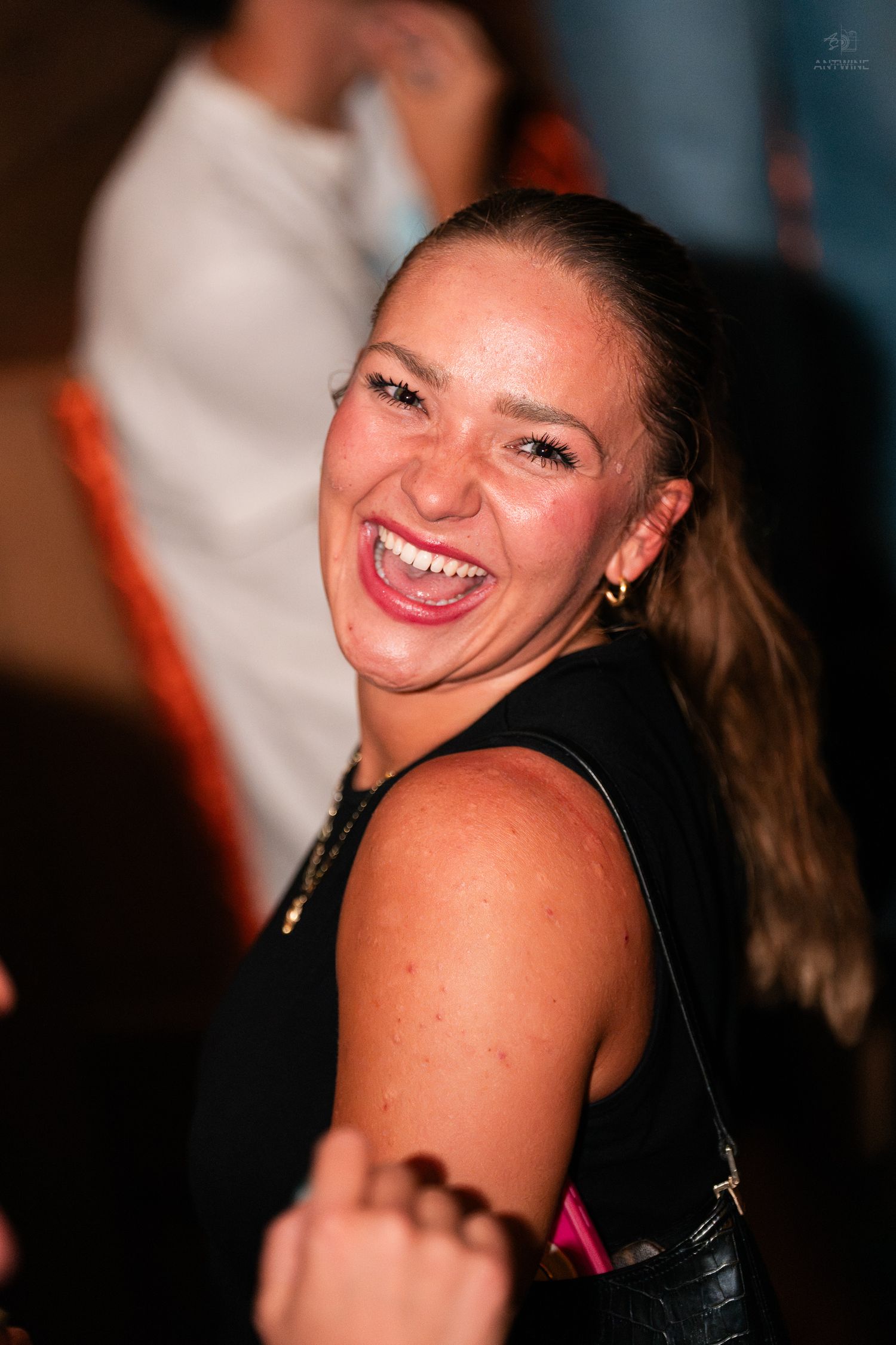 Laughing woman with a ponytail enjoying herself at a nightclub event.