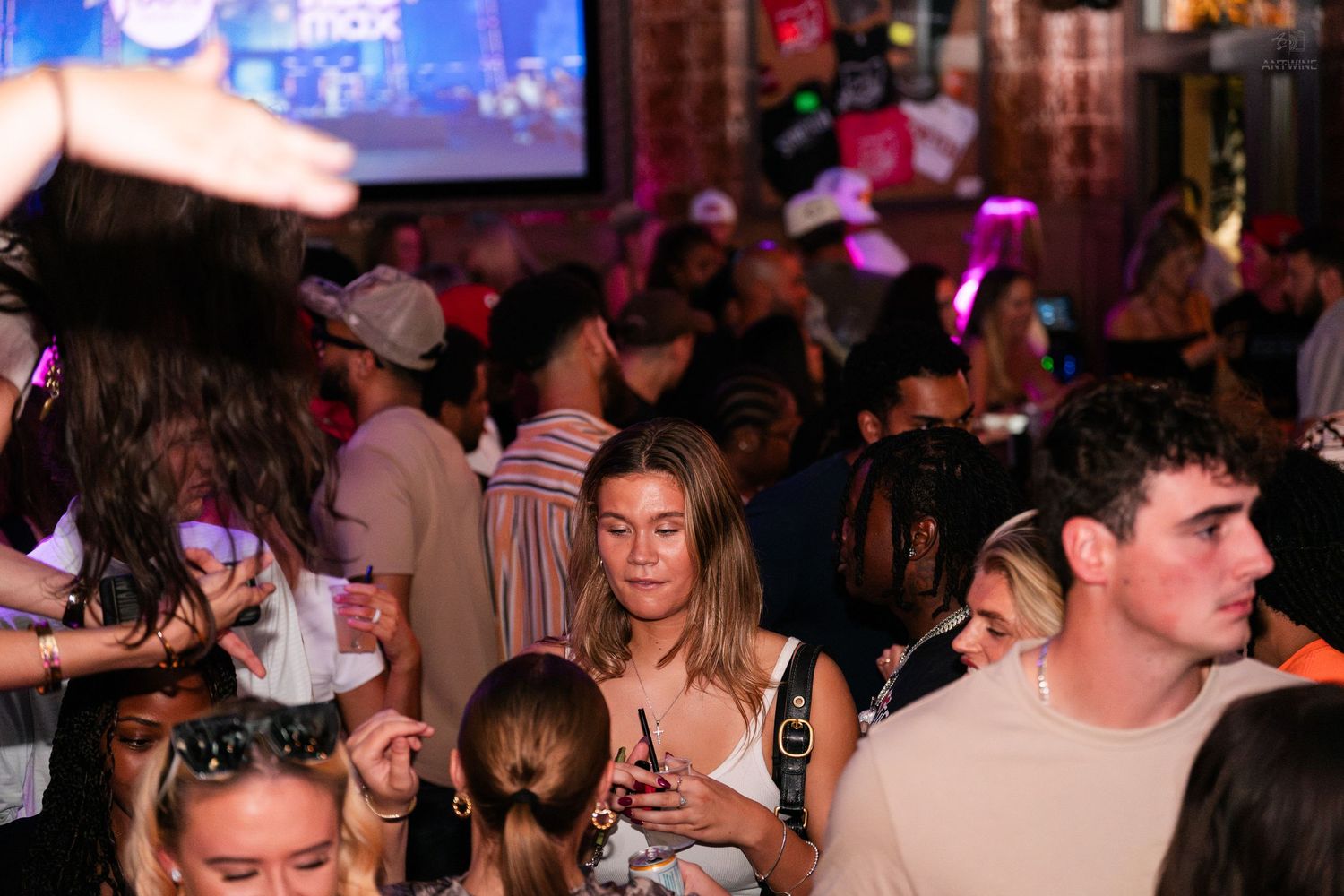 Diverse crowd of people socializing at a busy indoor bar or event venue.