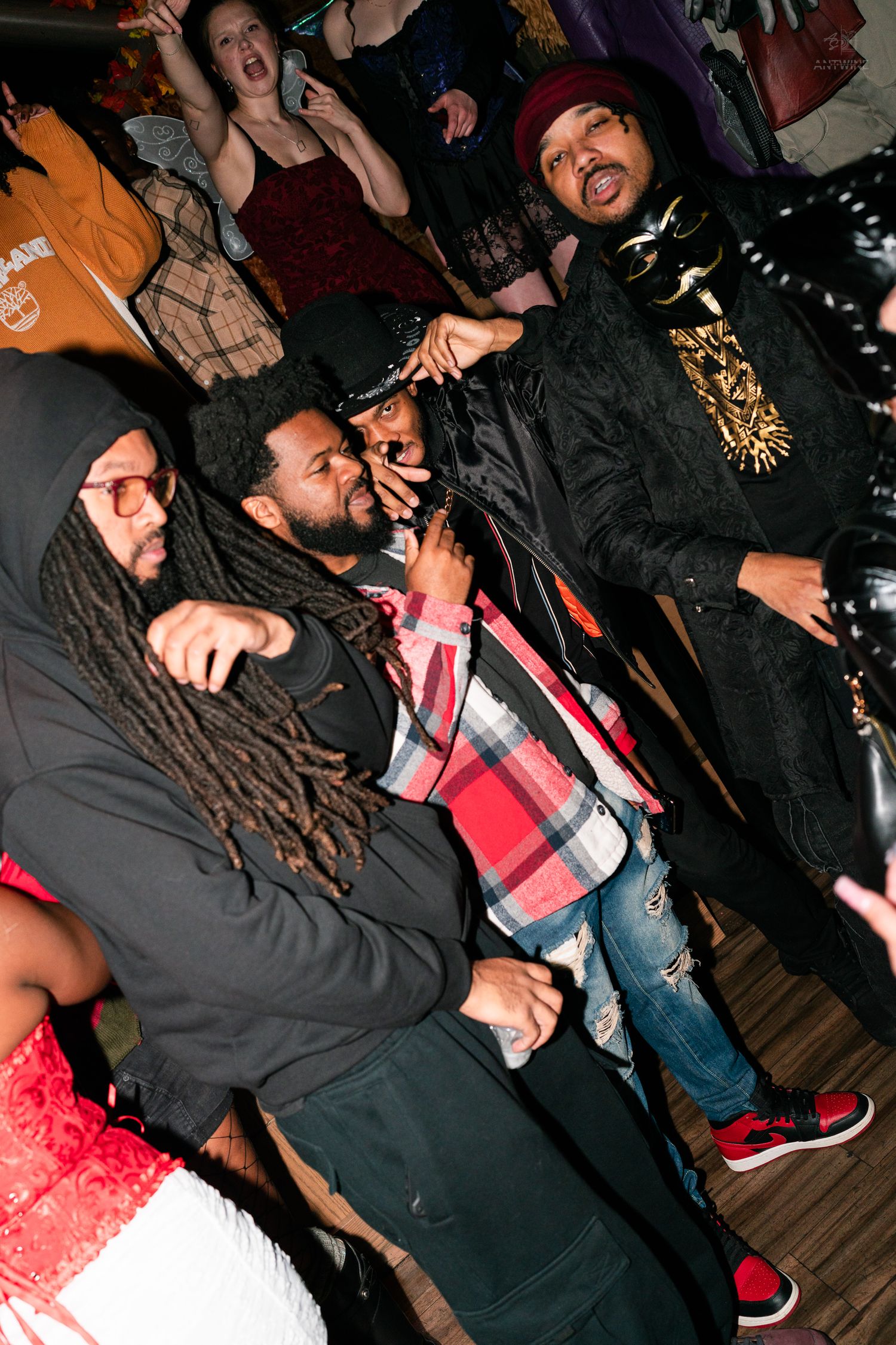 Friends in Halloween costumes laughing and celebrating together at a nightclub party.