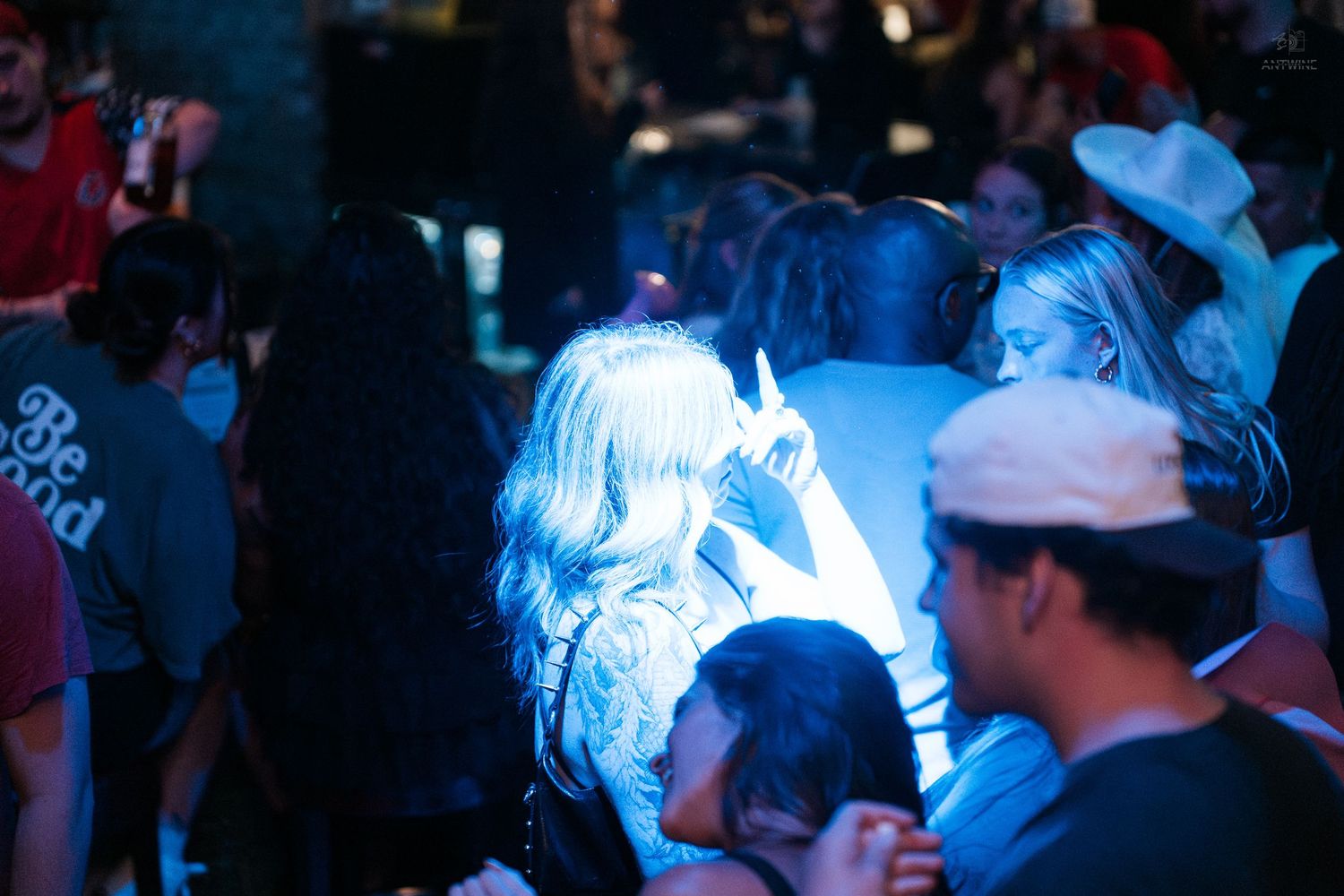 People gathered under blue stage lighting at a crowded indoor nightclub event.