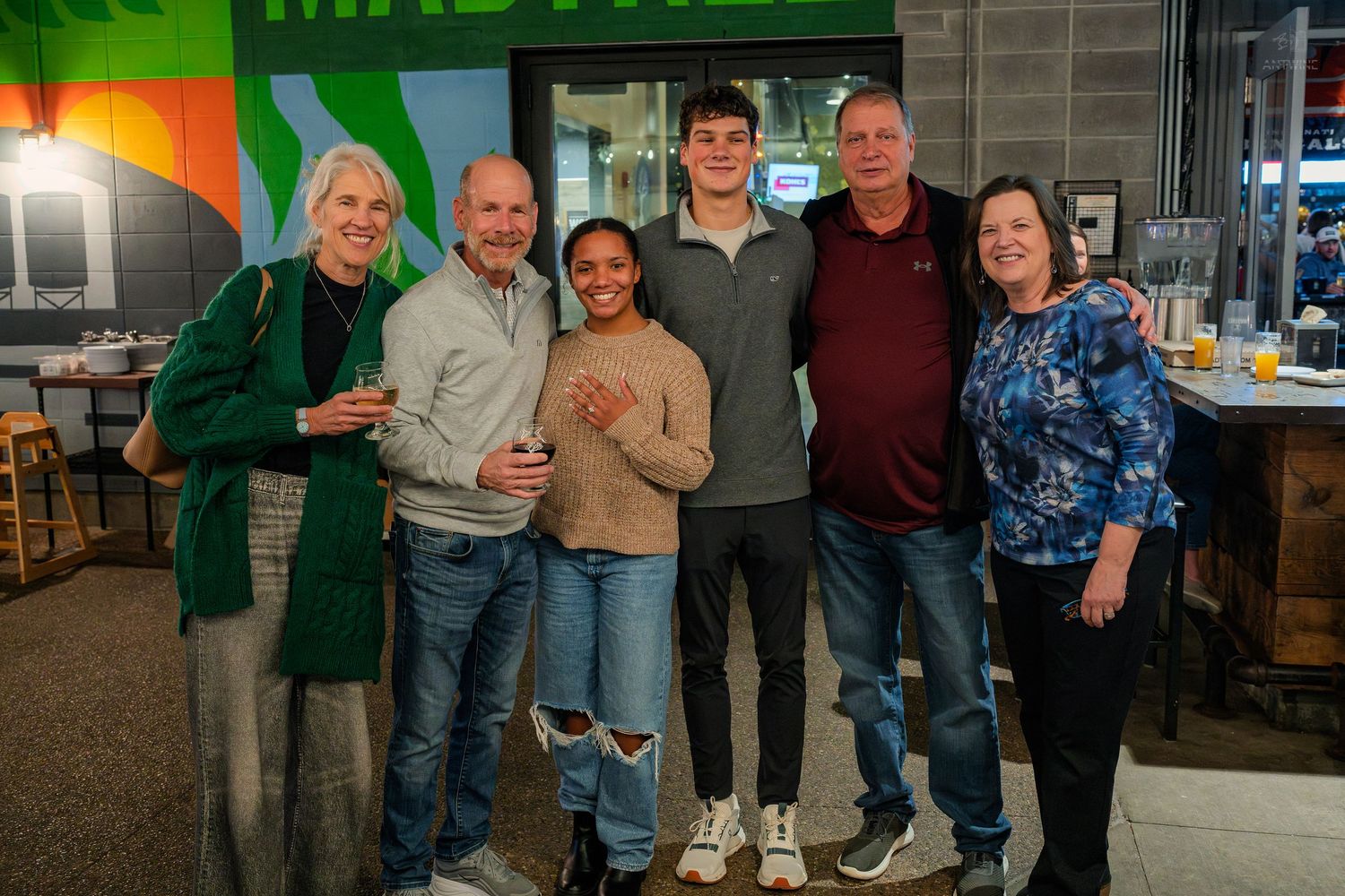 Group of six adults smiling together inside a Madtree Brewing restaurant.