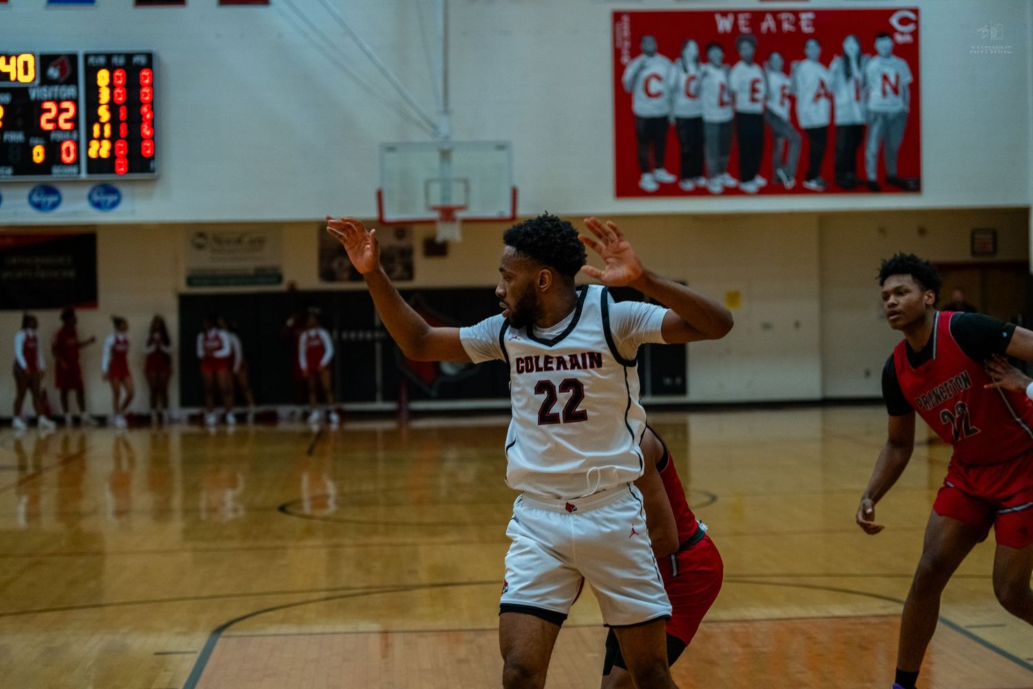 Coleman #22 basketball player signals with hands raised during a high school game.