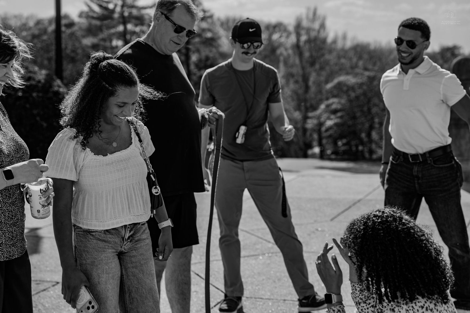 Black and white photo of a group of people standing outdoors on a sunny day.
