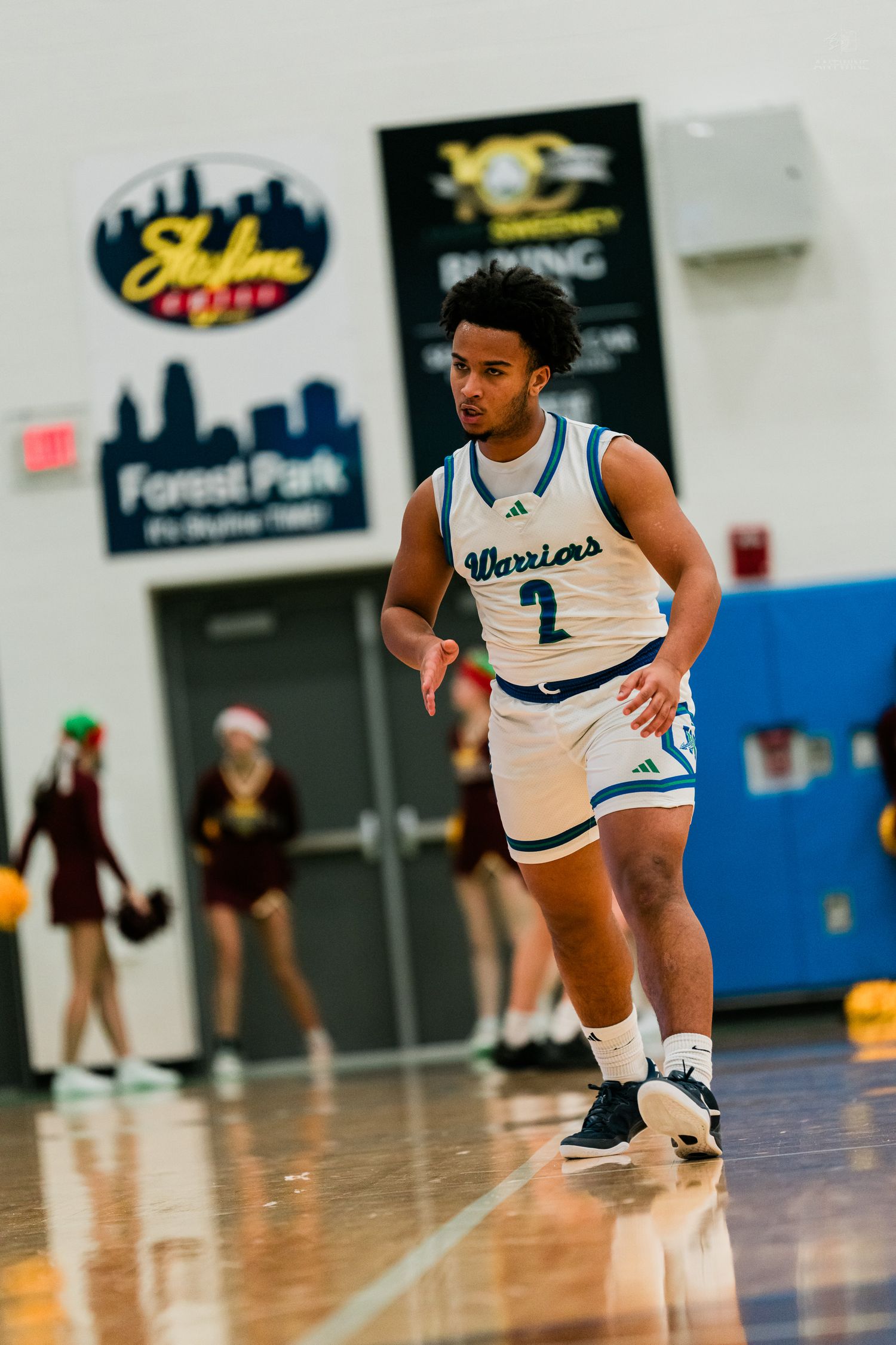 Warriors #2 basketball player dribbles on court during a high school game at Forest Park gym.
