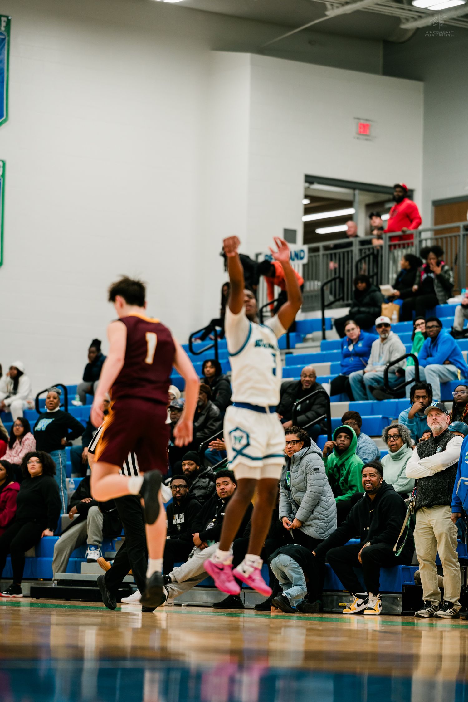 Warriors basketball player number 3 shoots a jump shot while fans watch from the bleachers during a home game.