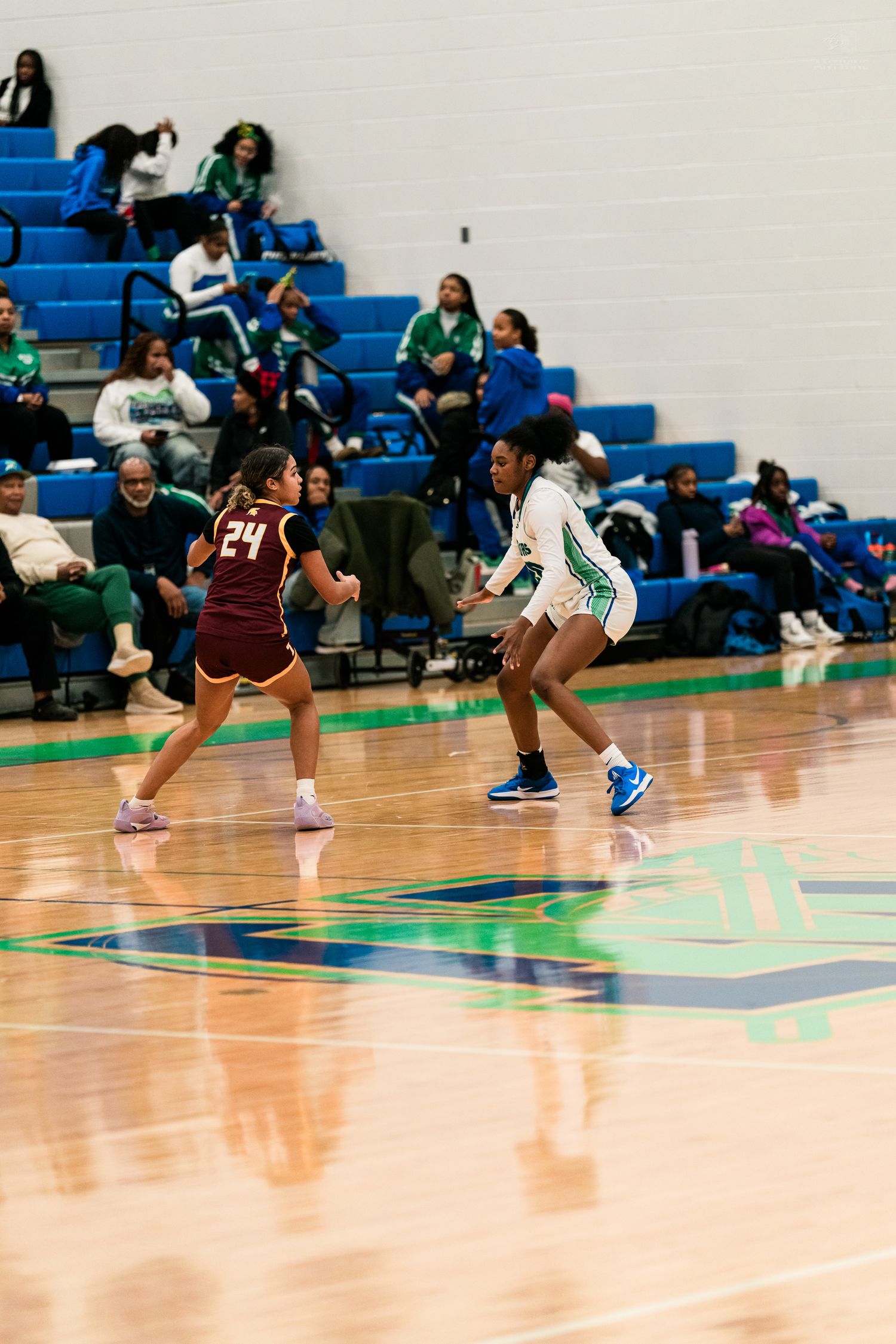 A Warriors player guards Turpin number 24 during a girls high school basketball game on a blue court.