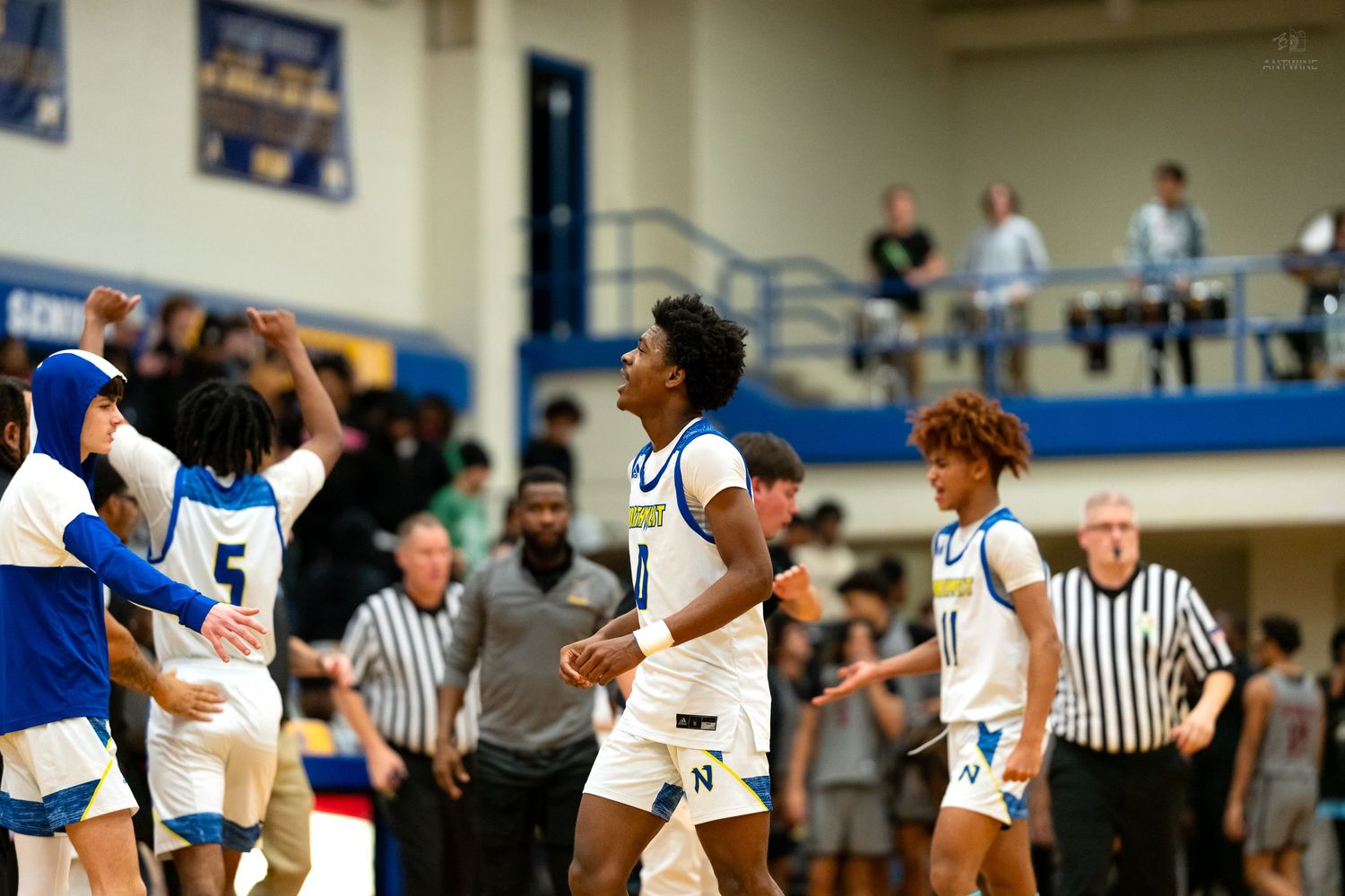 High school basketball players celebrate a big moment during an indoor gymnasium basketball game.
