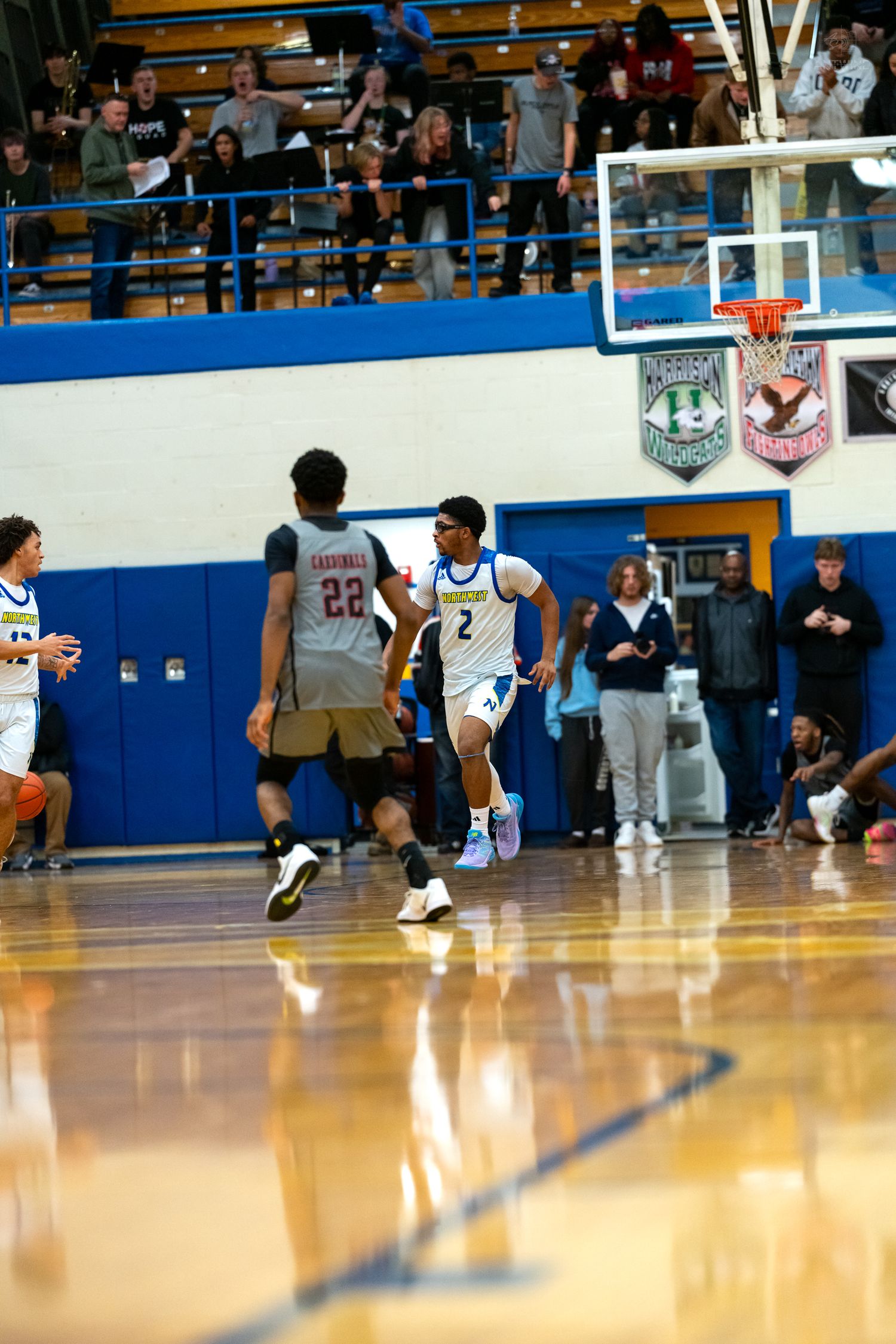 Player #2 in blue dribbles past defender #22 during a high school basketball game in a packed gymnasium.
