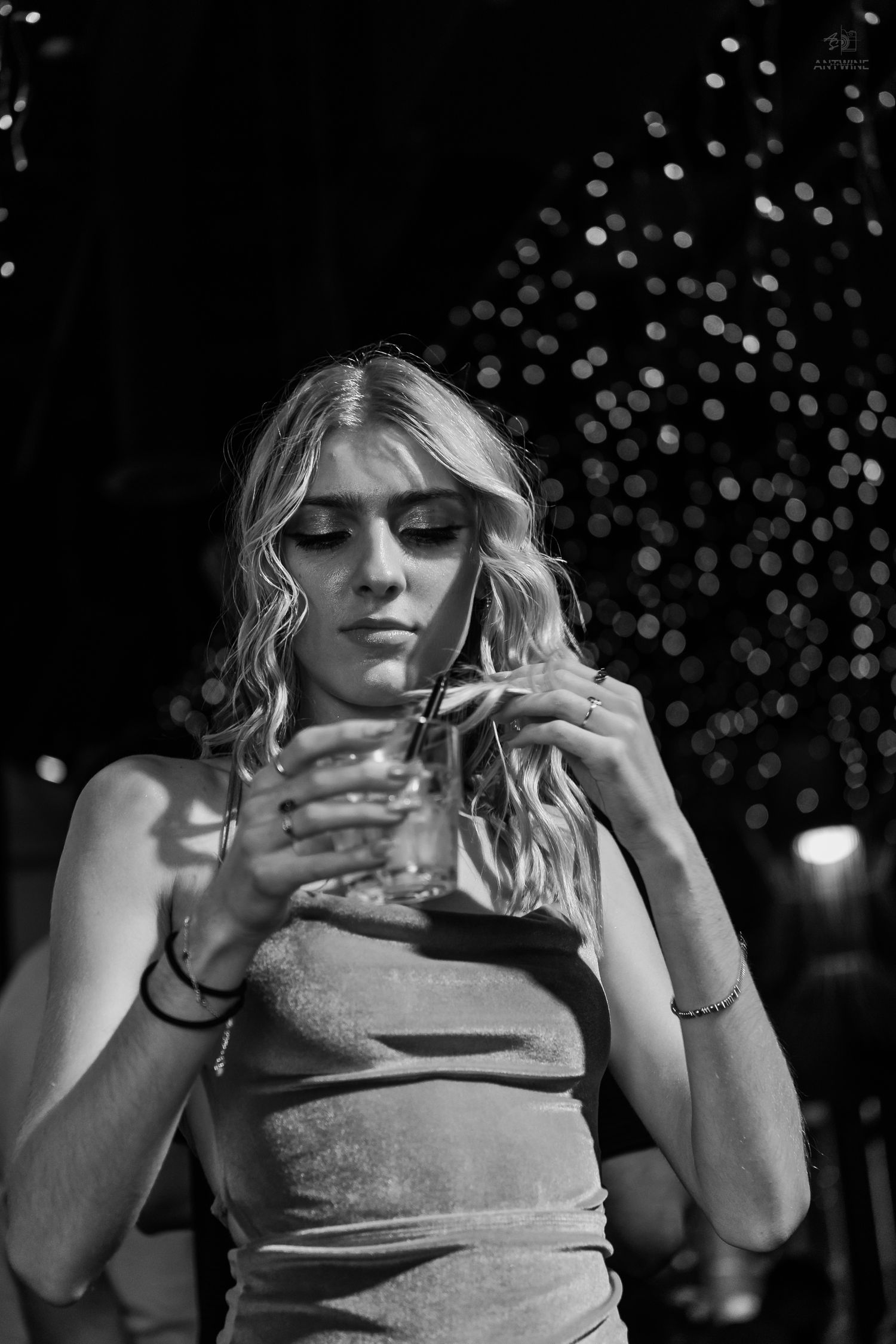 Blonde woman in velvet dress looking down at her drink at a nightclub.