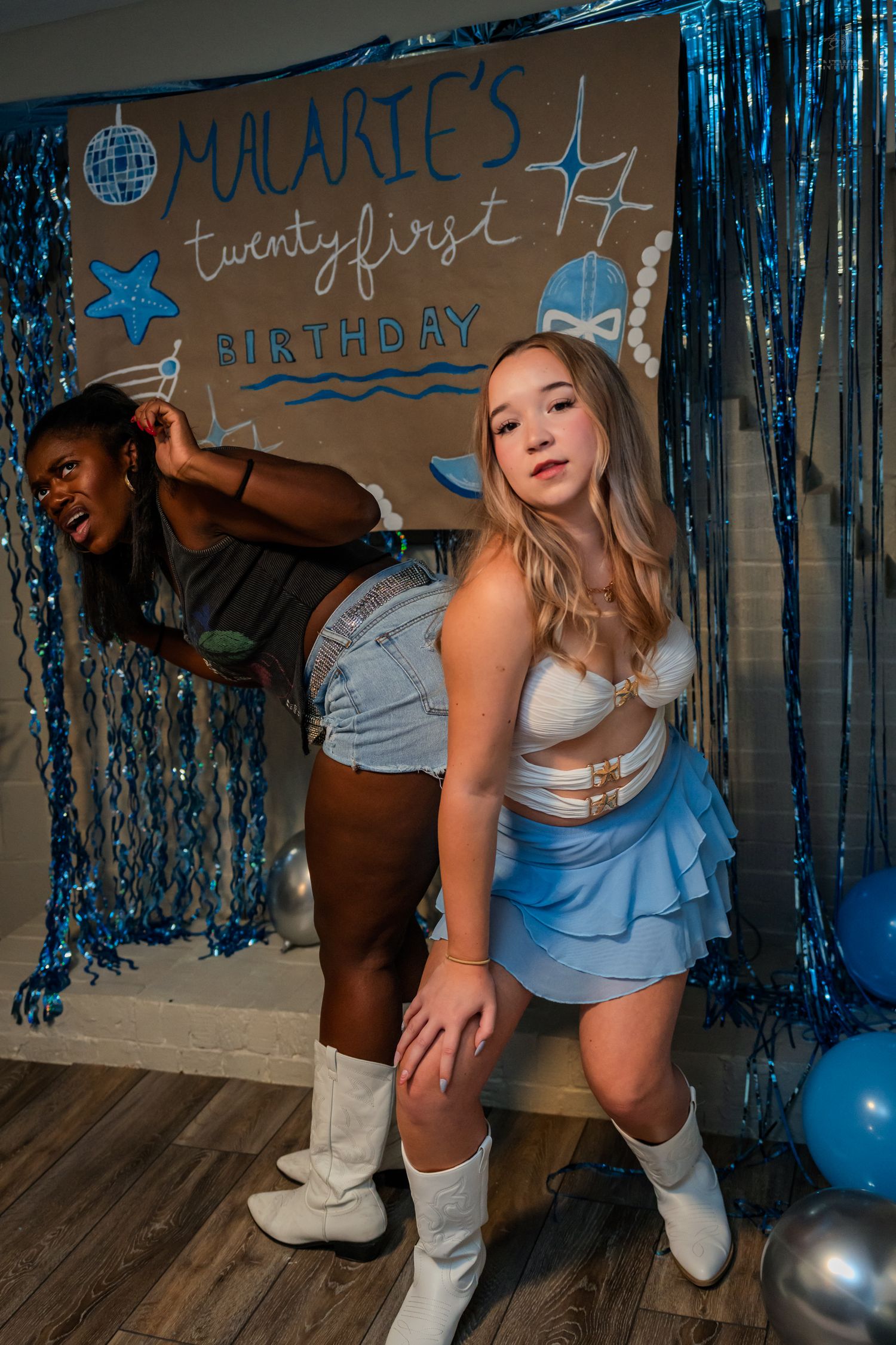 Two women strike playful poses at Malarie's twenty-first birthday party with blue balloons.