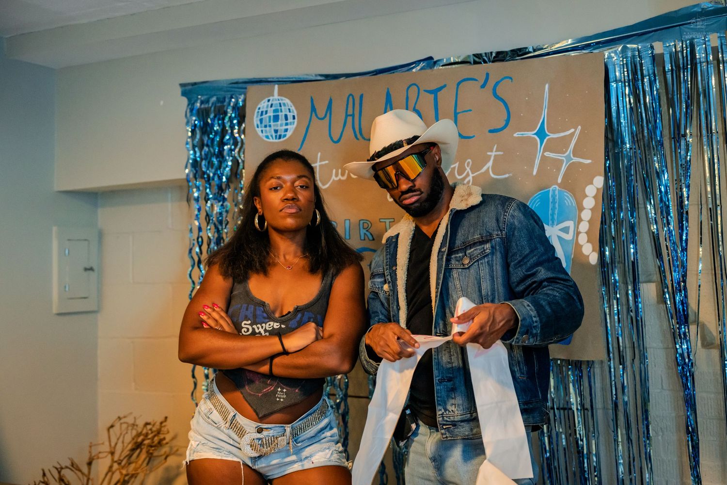 Man and woman pose together at Malarie's birthday party with blue tinsel backdrop.