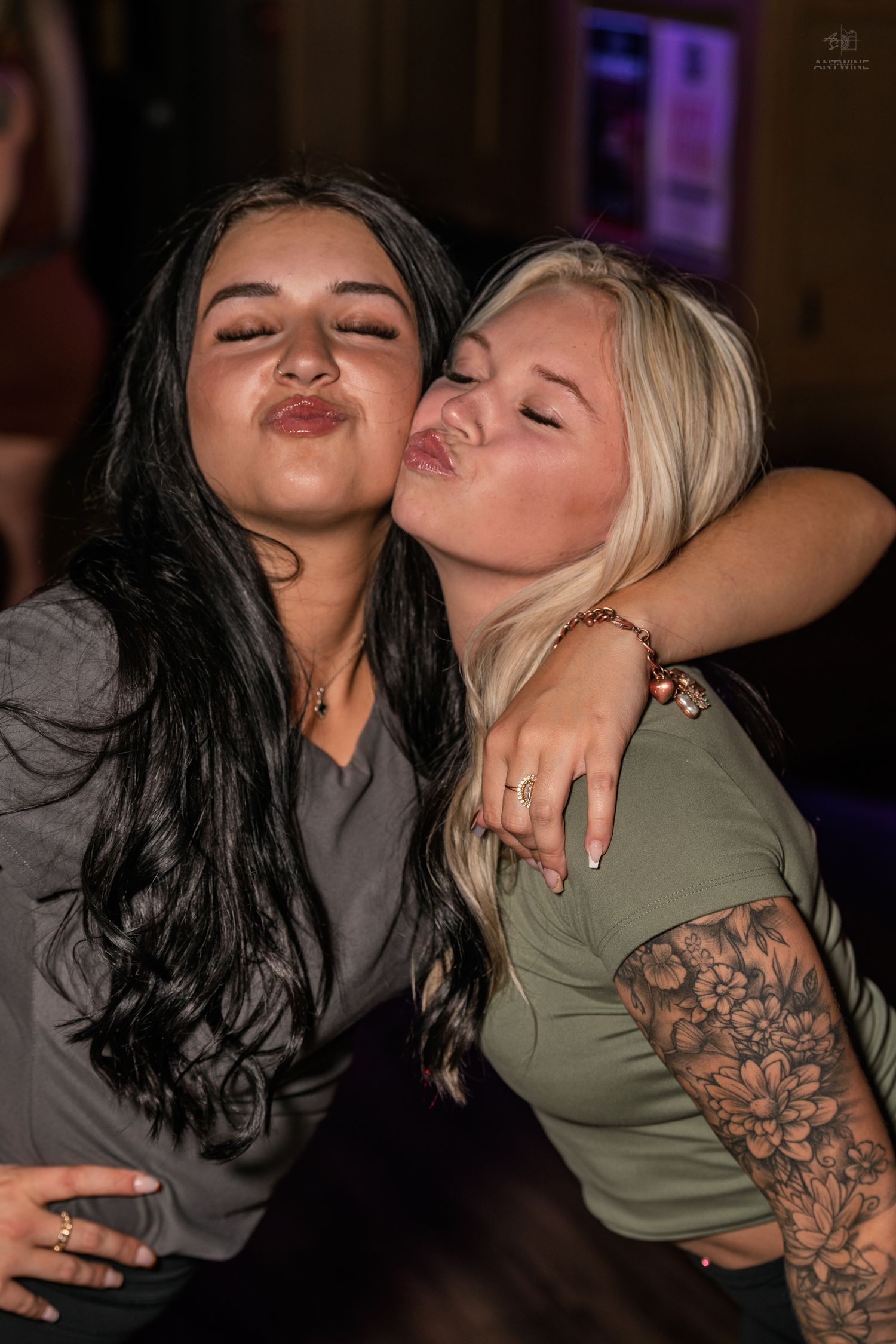 Two young women making duck faces pose for a fun selfie at a nightclub.