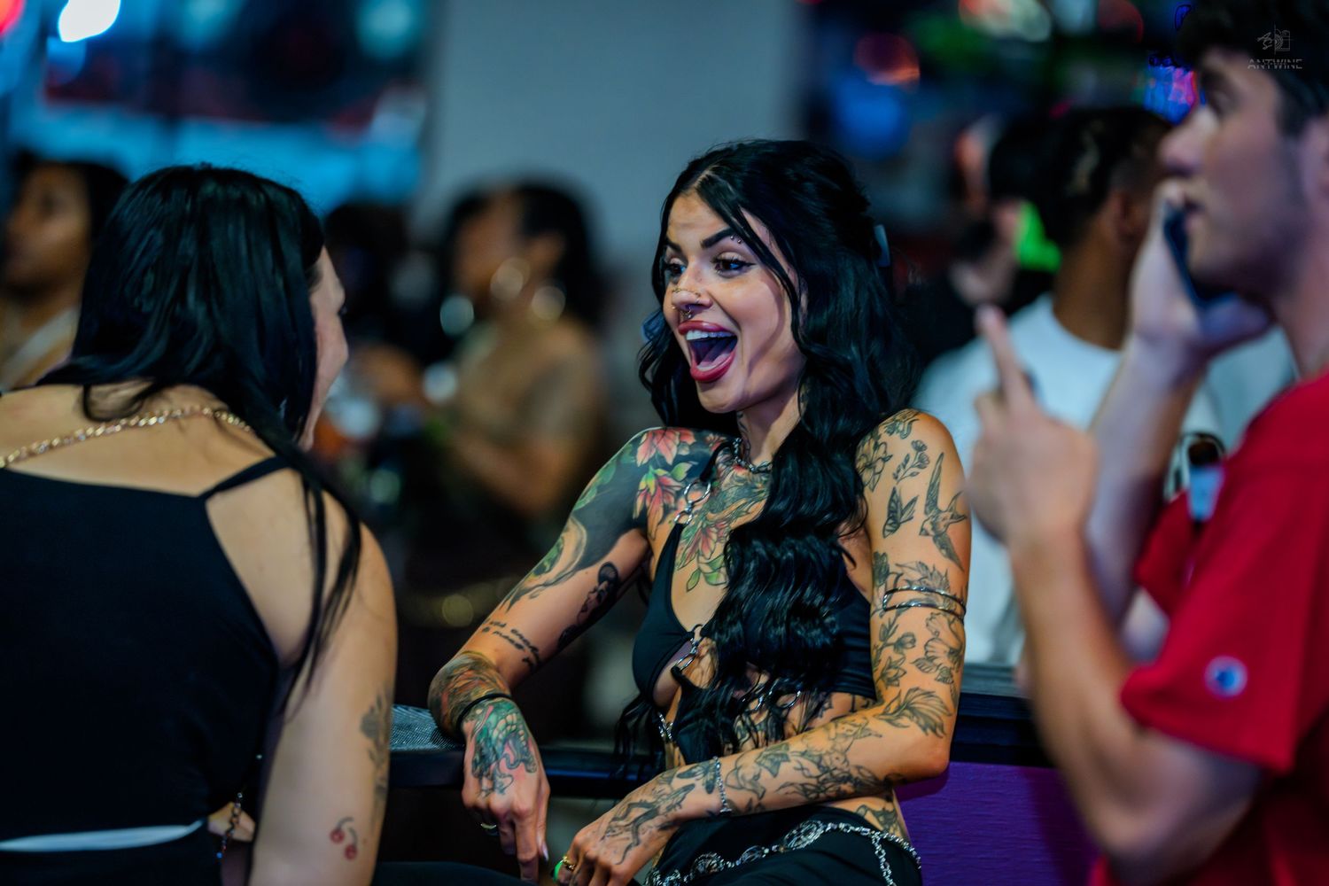 Heavily tattooed woman laughing joyfully at a nightclub party.