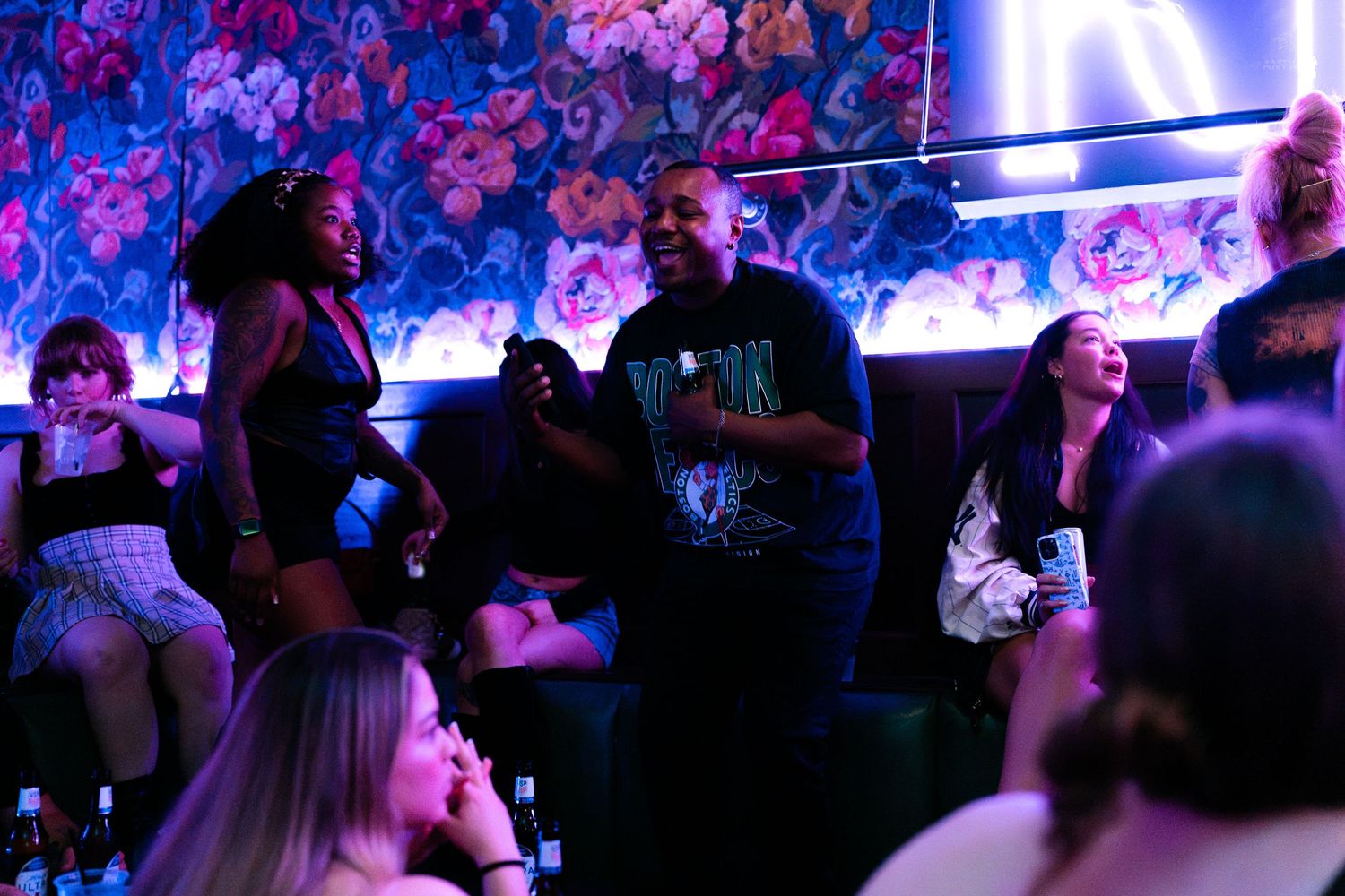 Group of friends laughing and socializing at a neon-lit nightclub.
