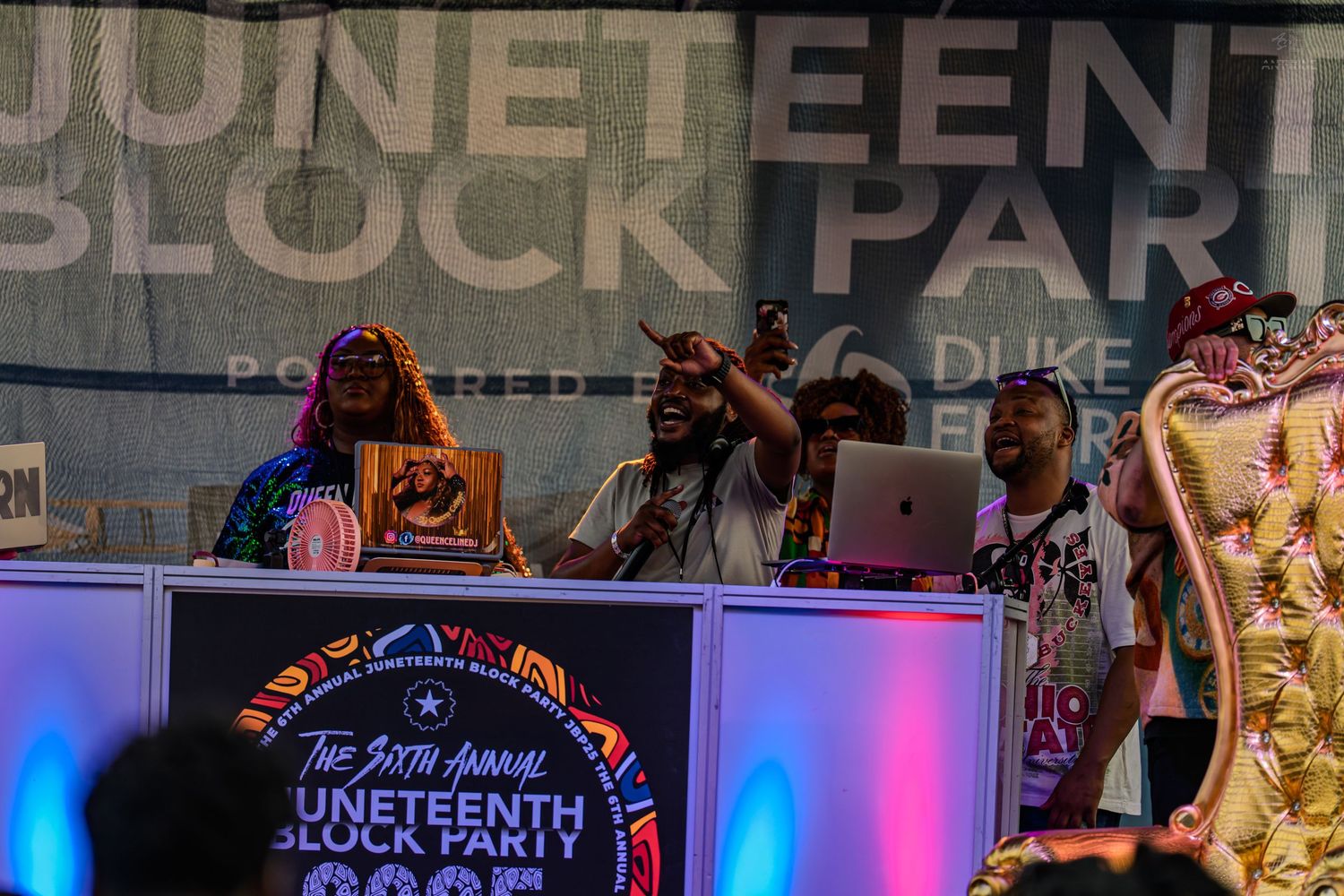 Energetic DJ performs at the annual Juneteenth Block Party event on an outdoor stage at night.