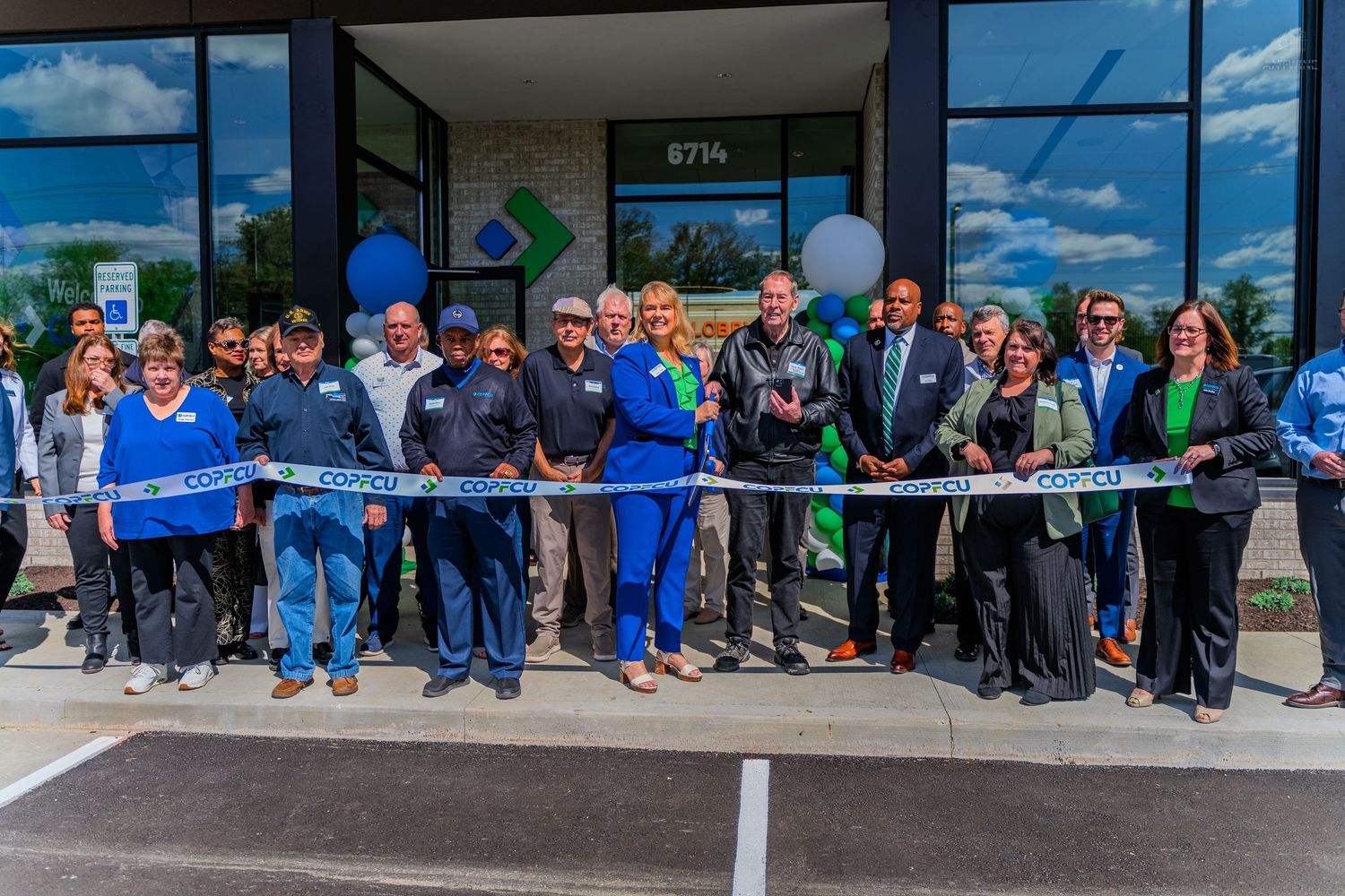 COPFCU credit union staff and community members celebrate a ribbon cutting ceremony at a new branch location.