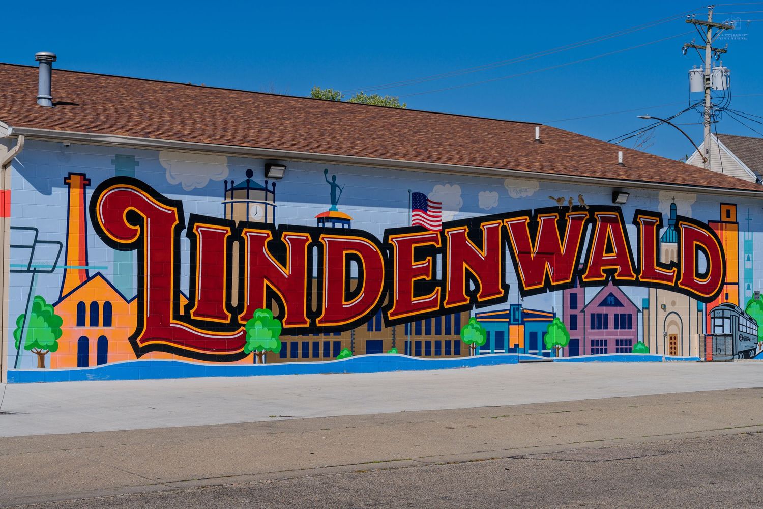 Colorful Lindenwald neighborhood mural painted on building exterior featuring bold red lettering and illustrated cityscape.
