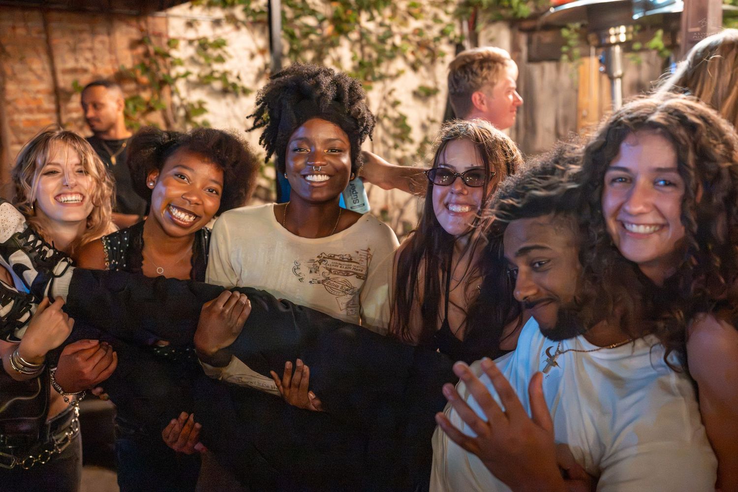 Diverse group of young friends smiling and laughing together at an outdoor social gathering at night.