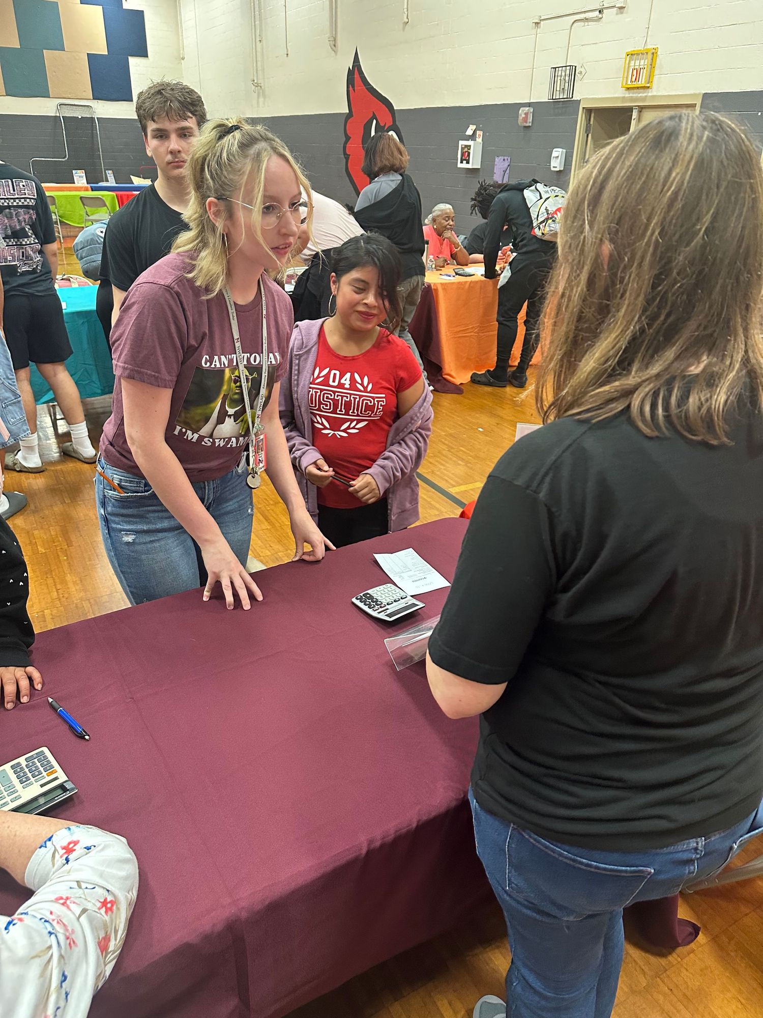 Students interact with a representative at a maroon table during a high school career fair event.