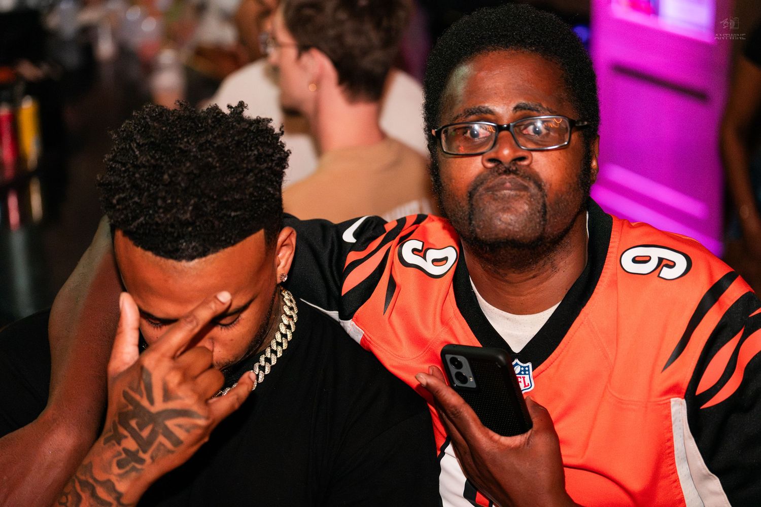 Two men in Bengals jerseys looking disappointed at a NFL watch party event.