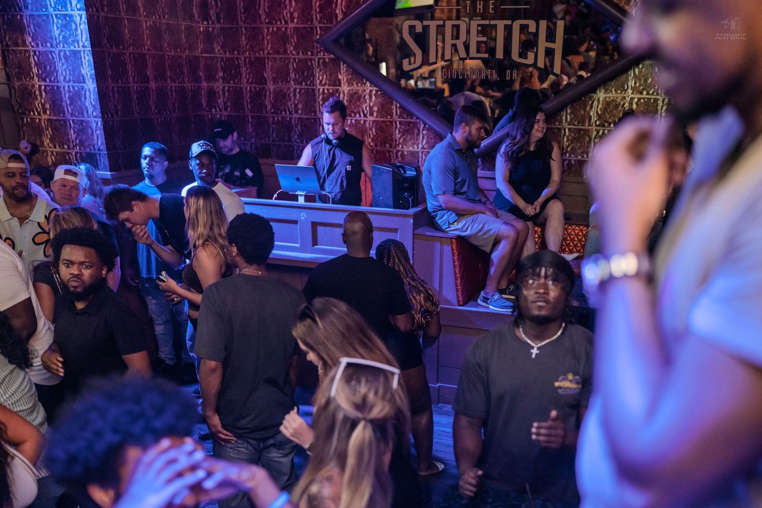 DJ spinning records at Stretch nightclub while diverse crowd enjoys the party.