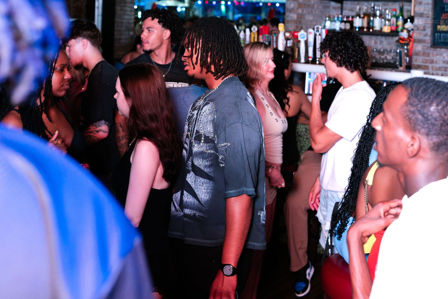 Diverse group of people socializing at a lively nightclub bar scene.