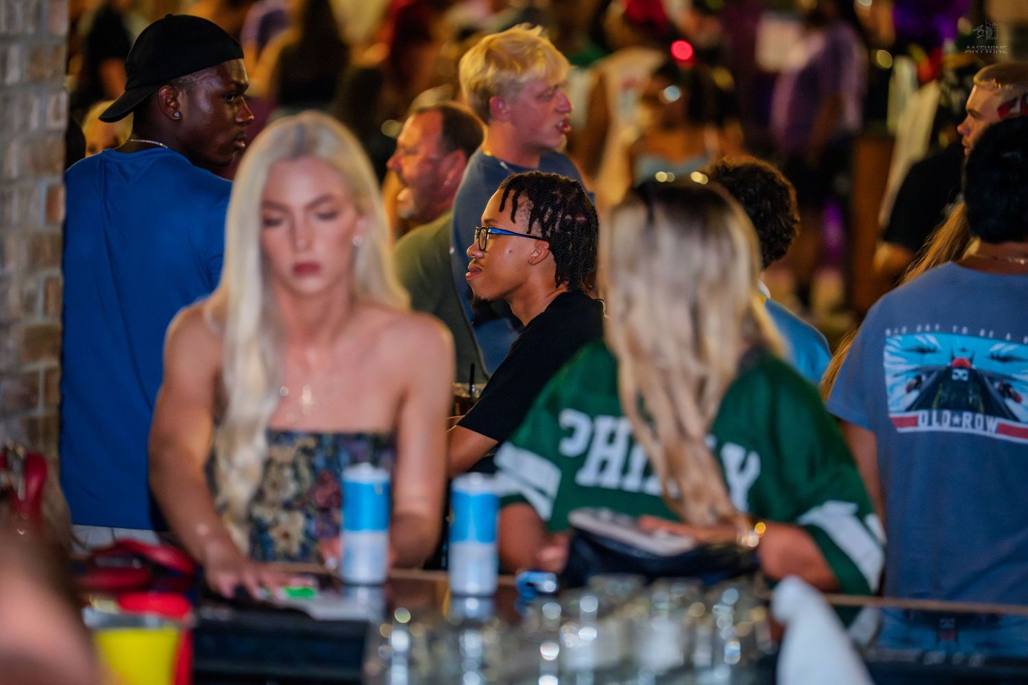 Crowd of people socializing at a busy bar or nightclub.