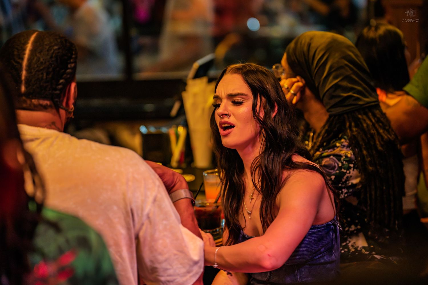 Woman holding a drink laughing and socializing at a vibrant nightclub party event.