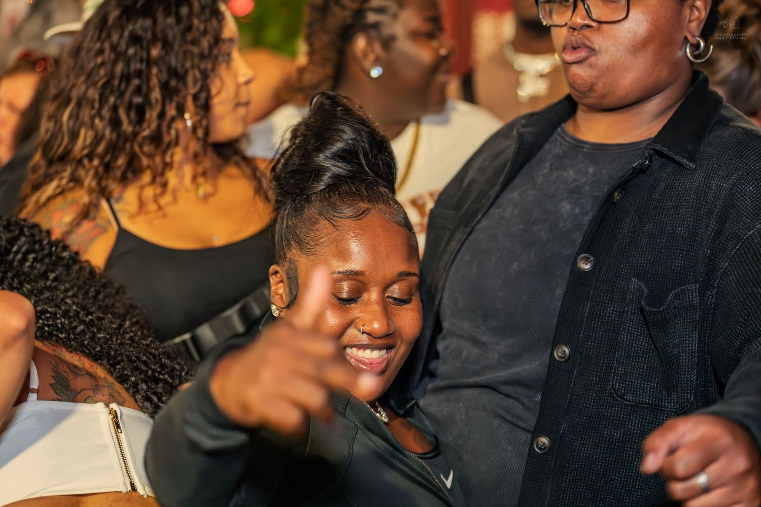 Two women smiling and dancing together at an outdoor nighttime party event.