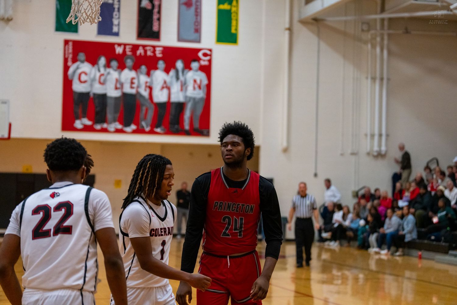 Basketball player #21 in red walks near opponents #22 and #1 on court.