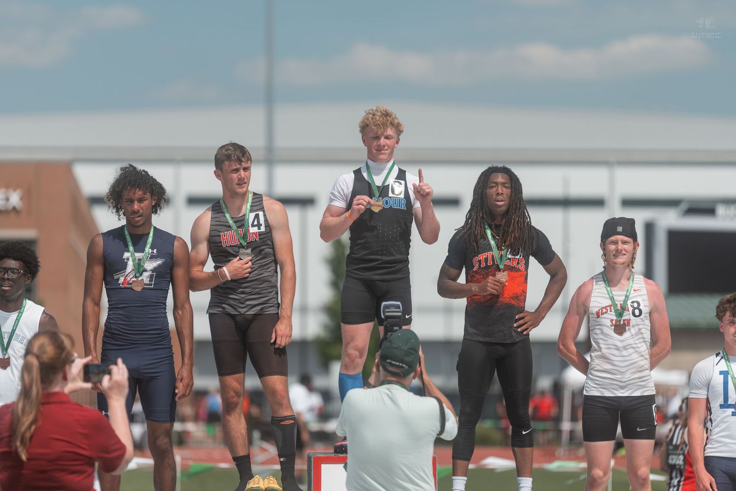 First place high school sprinter celebrates with peace sign on OHSAA Division IV 200 meter dash podium.