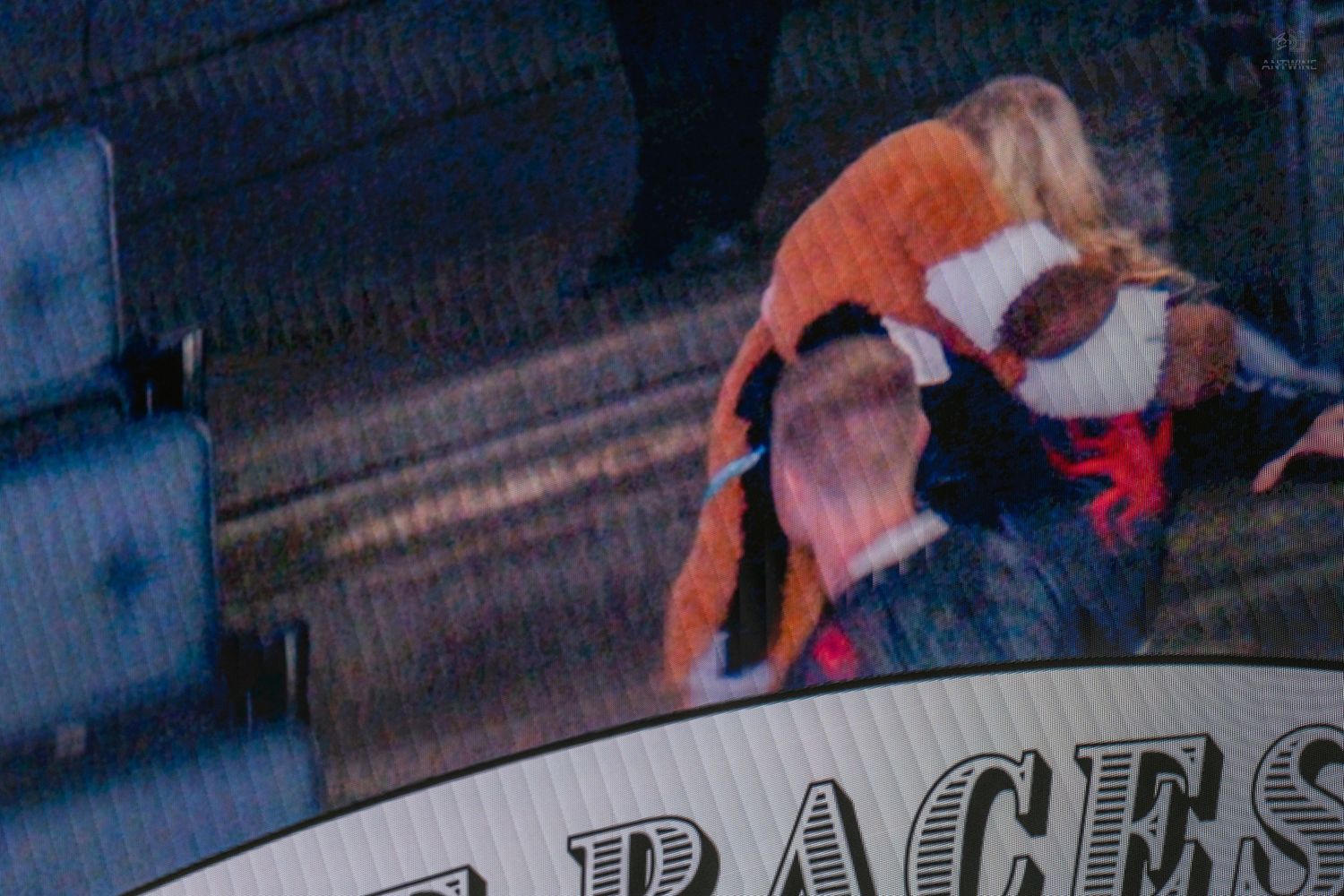 Two fans embrace enthusiastically while watching a live sporting event in the stadium stands.