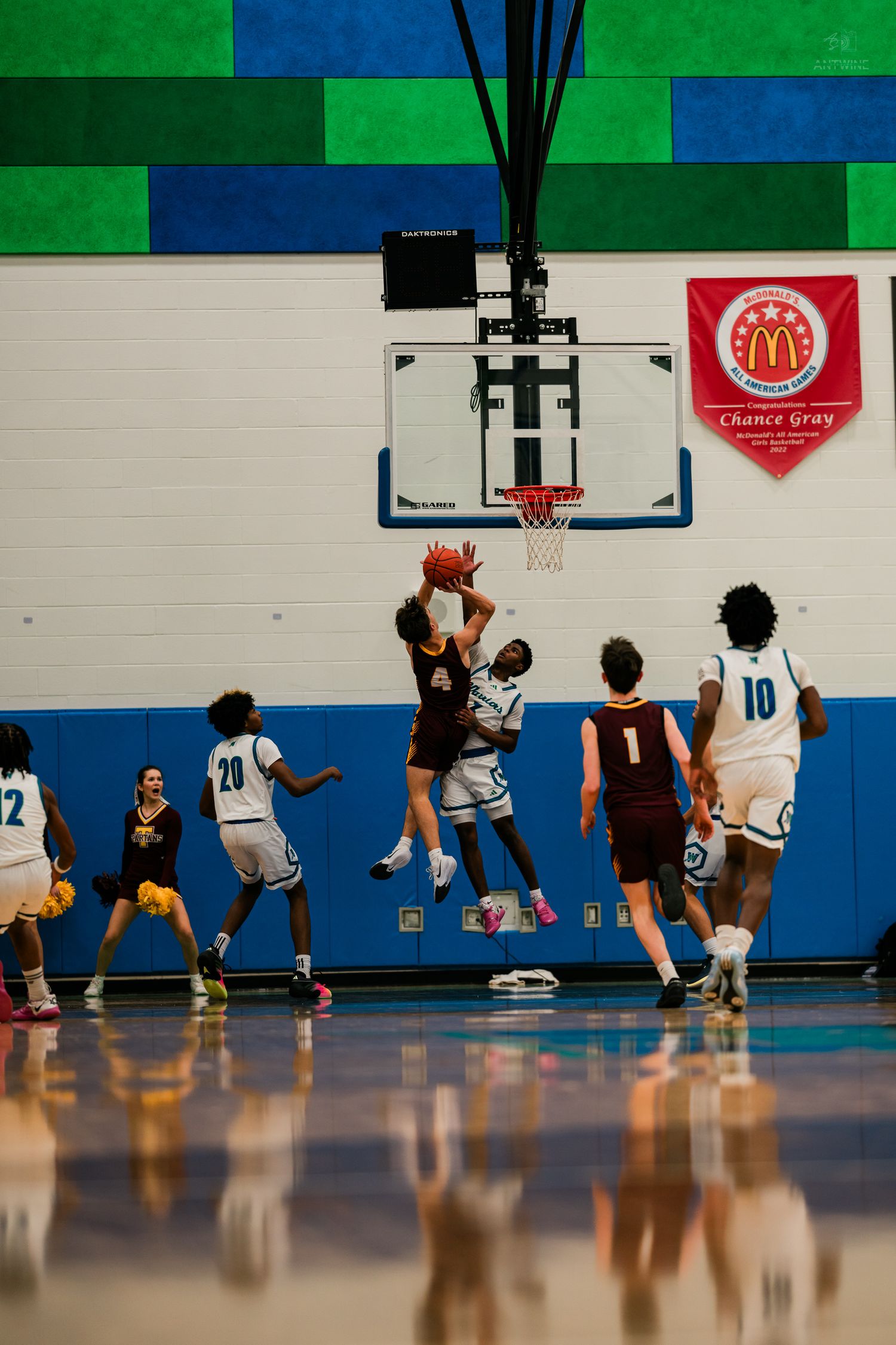 Players battle for a rebound near the basket during a Warriors home basketball game under the McDonalds banner.