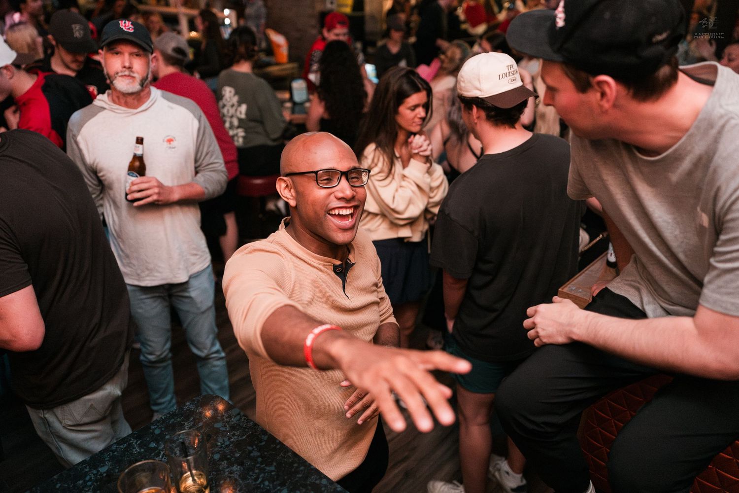 Excited bald man reaching out toward friends at a lively indoor party event.