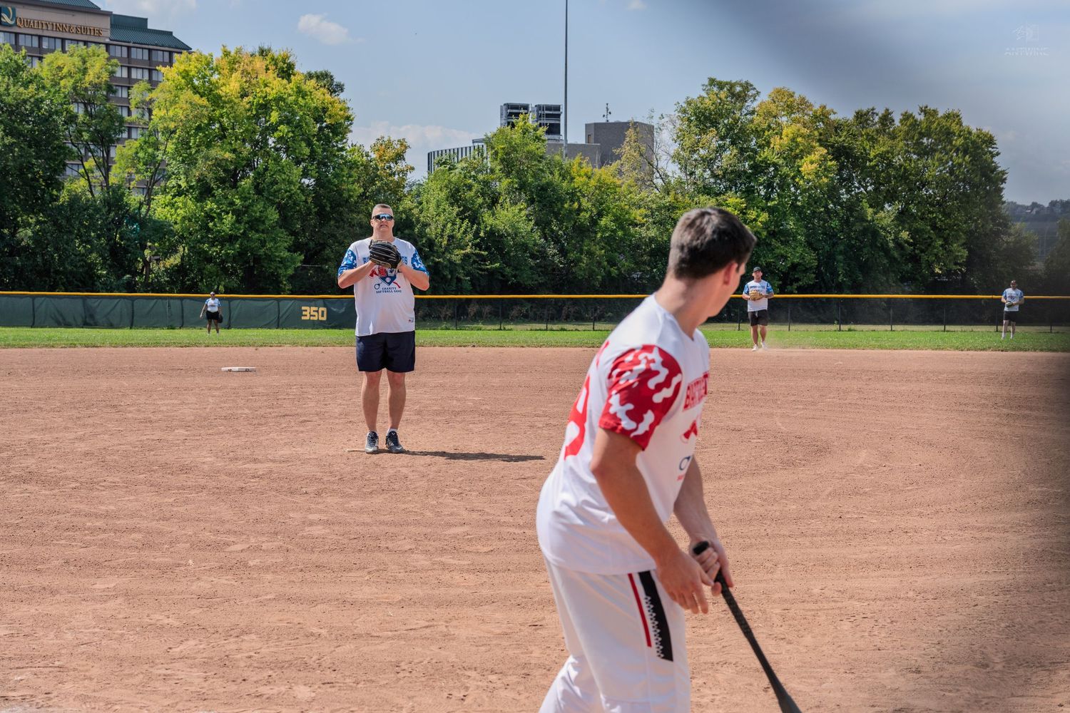 Two softball players on dirt field during sunny outdoor game.