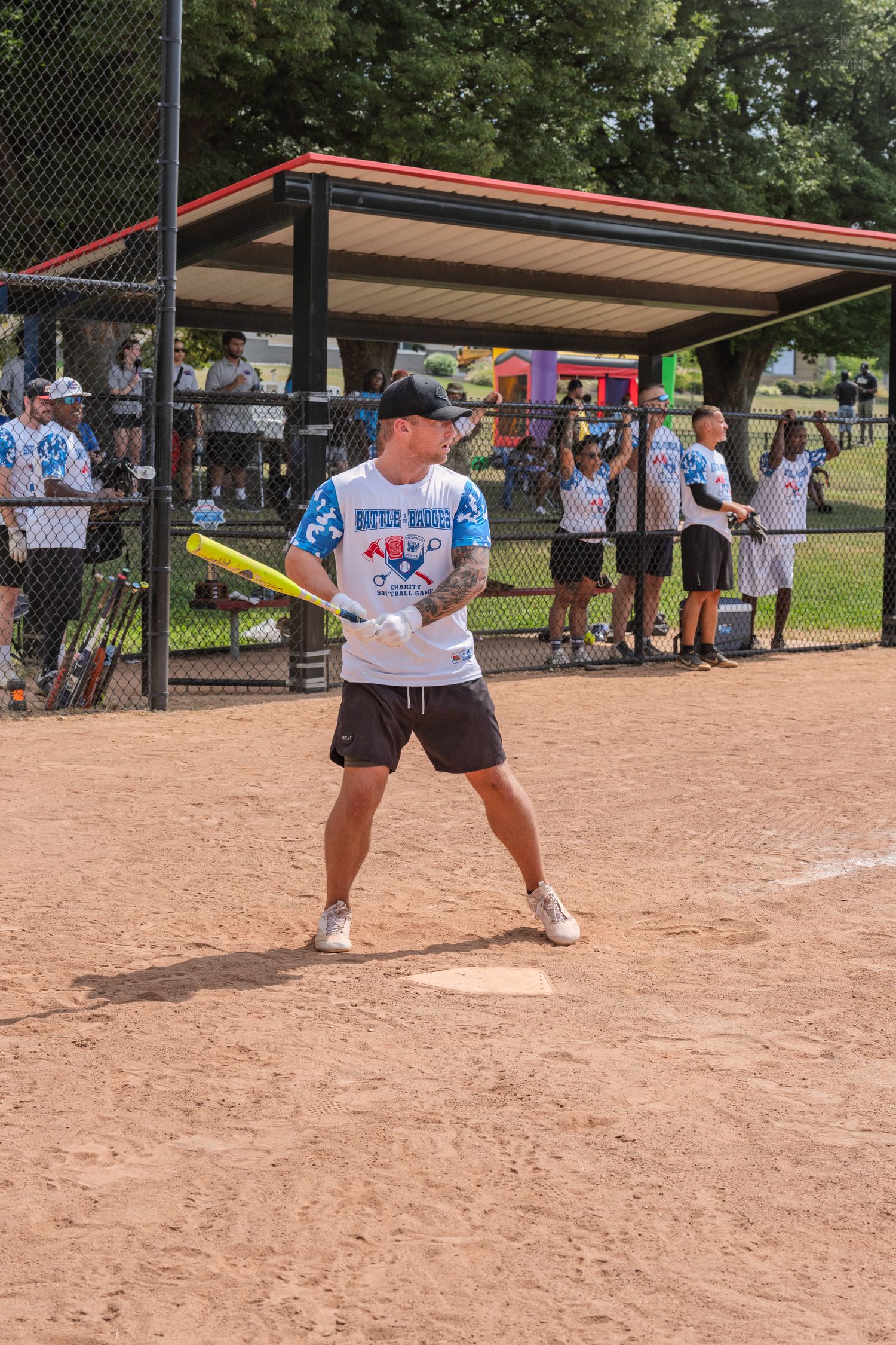 A batter stands ready at home plate during a recreational softball game on a sunny day.