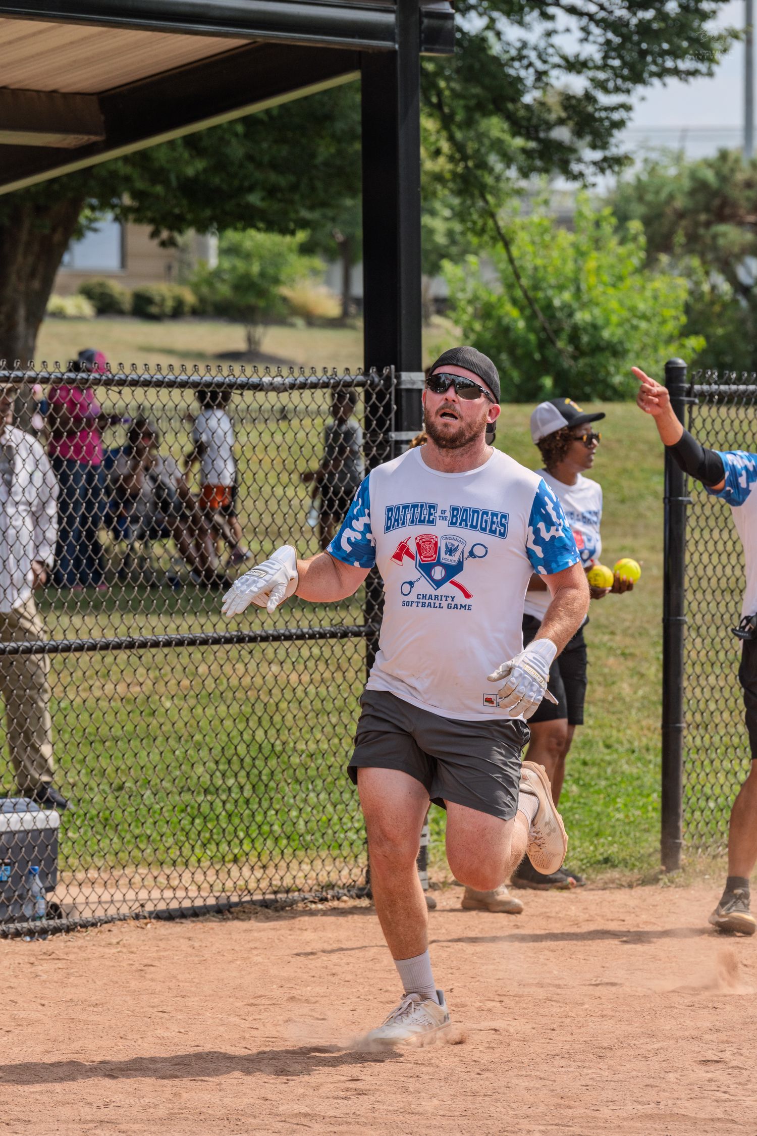 Athlete runs bases wearing a Bridges softball game jersey during an outdoor charity event.