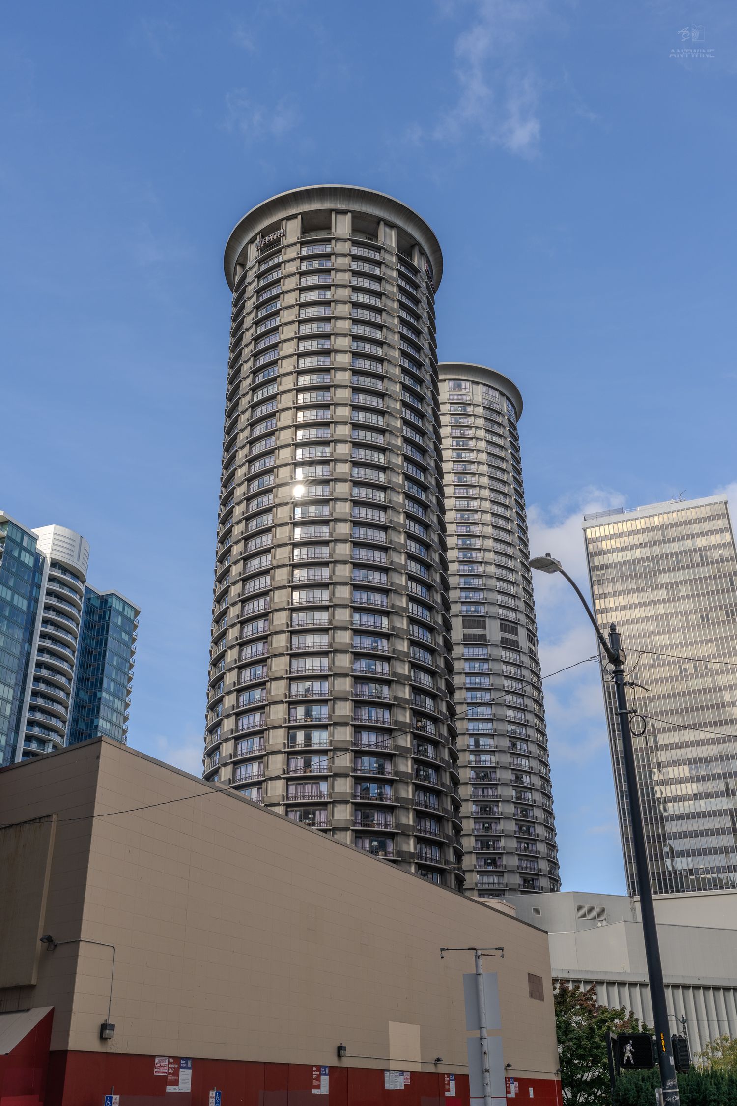 Twin cylindrical residential skyscrapers rising against blue sky in downtown Seattle.