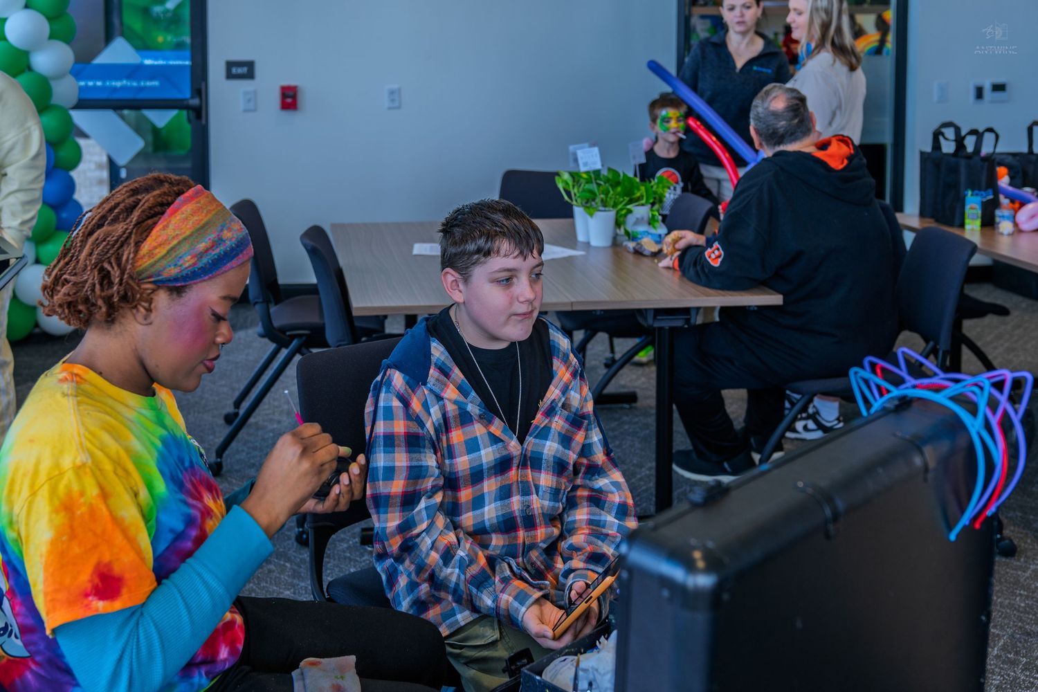 Two teens play video games together at a COPFCU community grand opening event indoors.