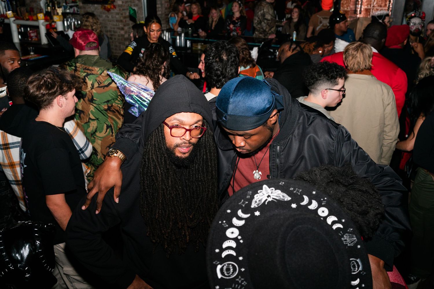 Crowd of people dancing and socializing at a lively Halloween party event.
