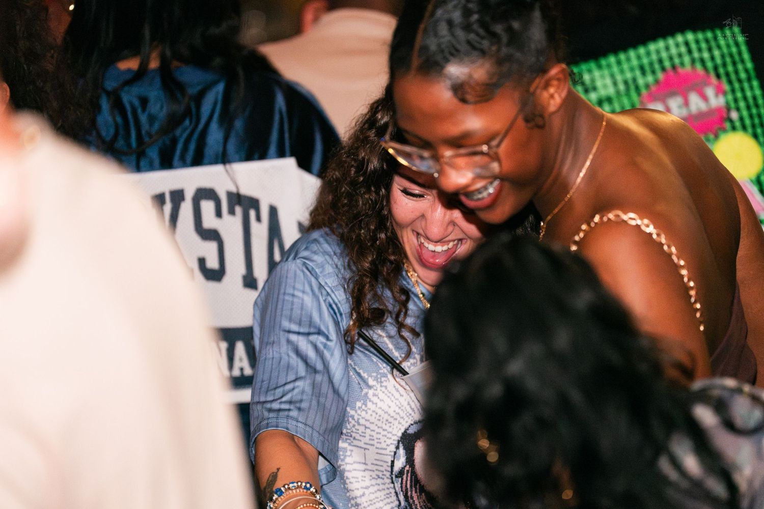 Two women laughing and dancing together at a nightclub event.