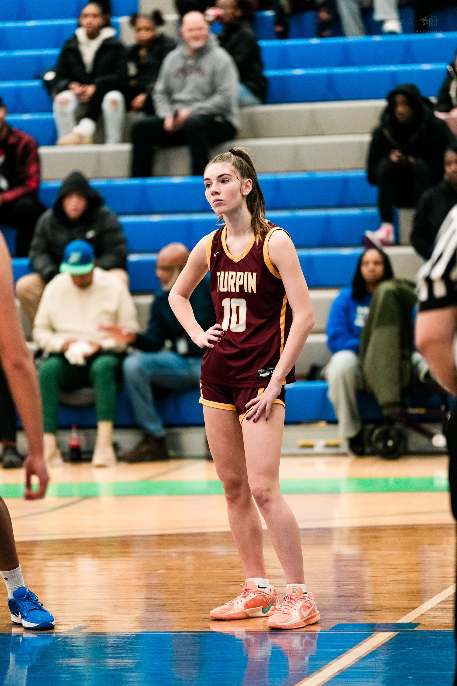 Turpin High School female basketball player number 10 stands with hands on hips during an indoor basketball game.
