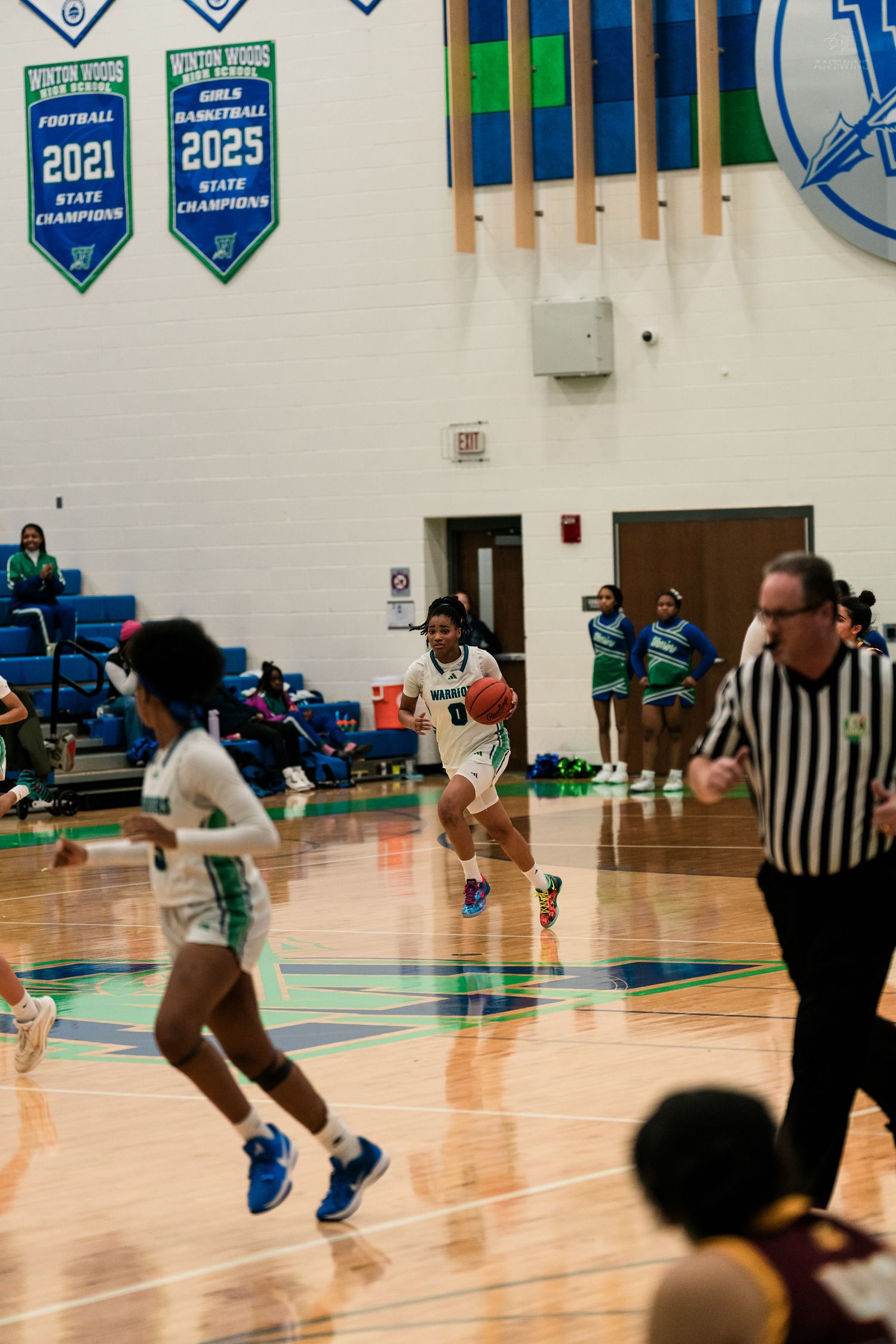 A Winton Woods girls basketball player in green drives toward the basket during a home game.