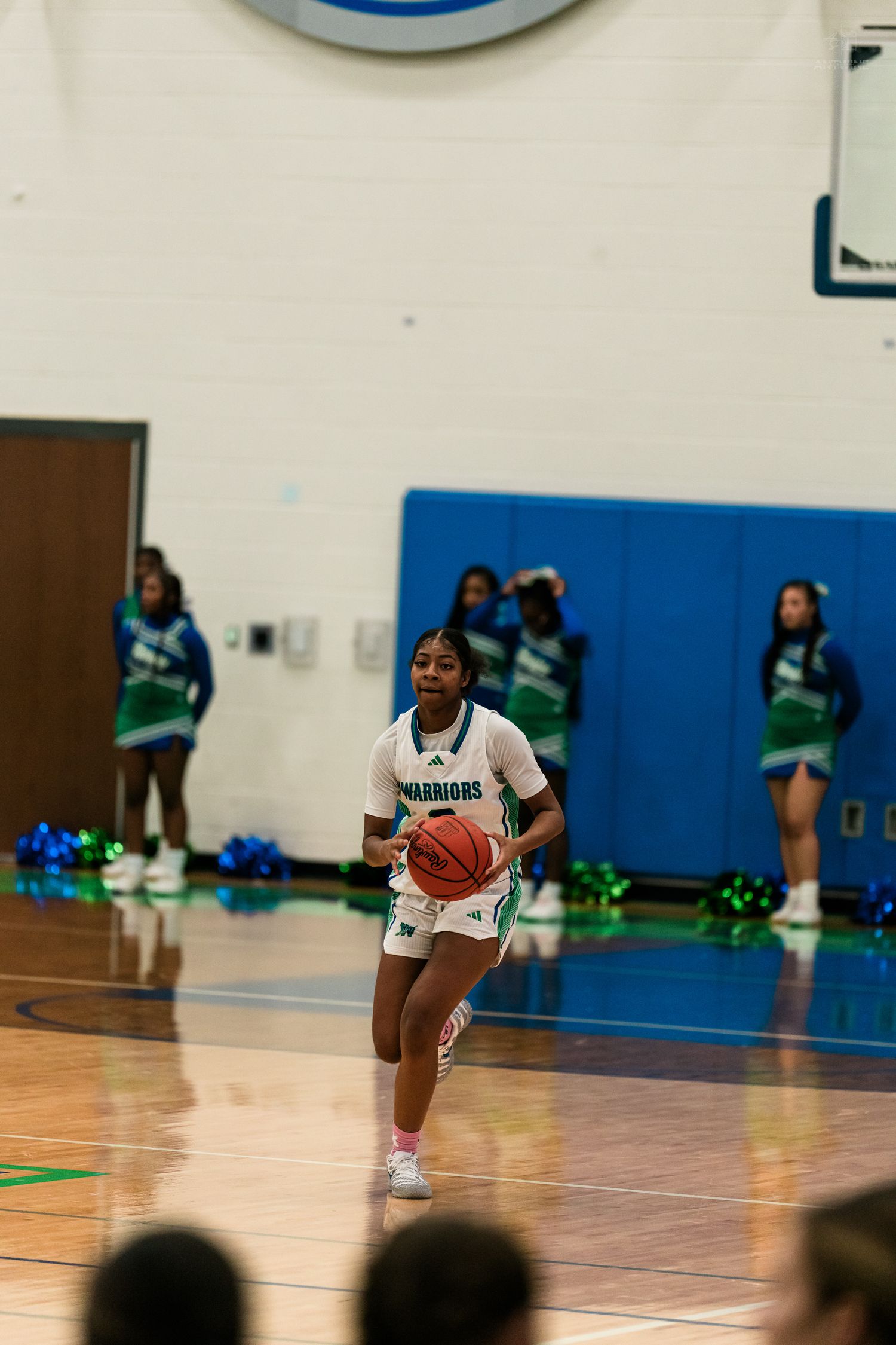 Warriors girls basketball player in teal uniform prepares to shoot during high school game.