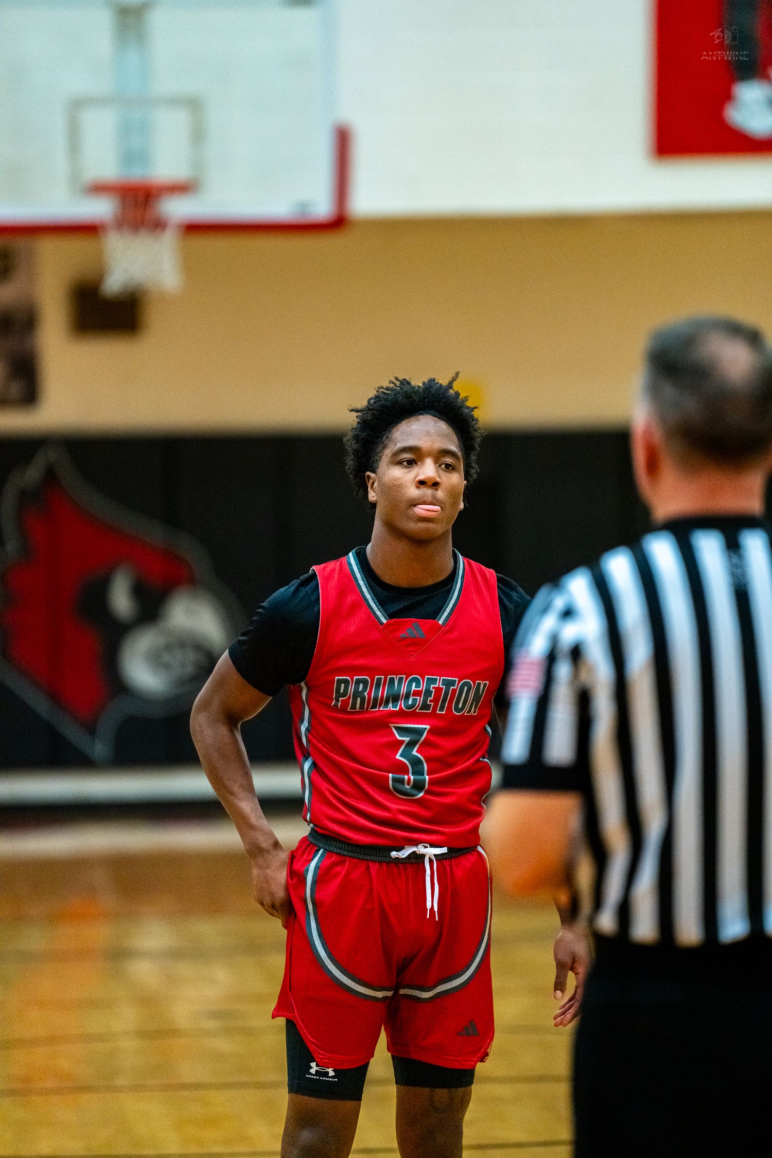 Princeton #3 basketball player stands at free throw line facing referee in gym.