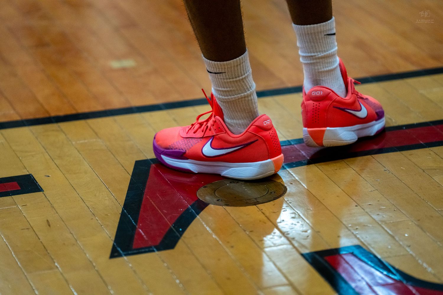 Close-up of basketball player wearing red Nike sneakers standing on hardwood court during game.